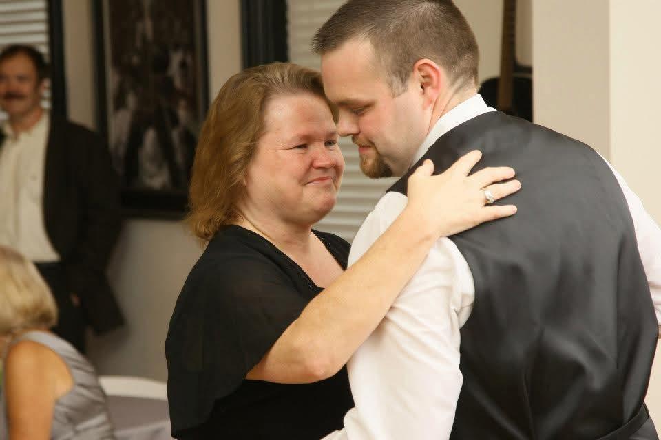 A mother and son share a heartfelt moment while dancing together at a family celebration.