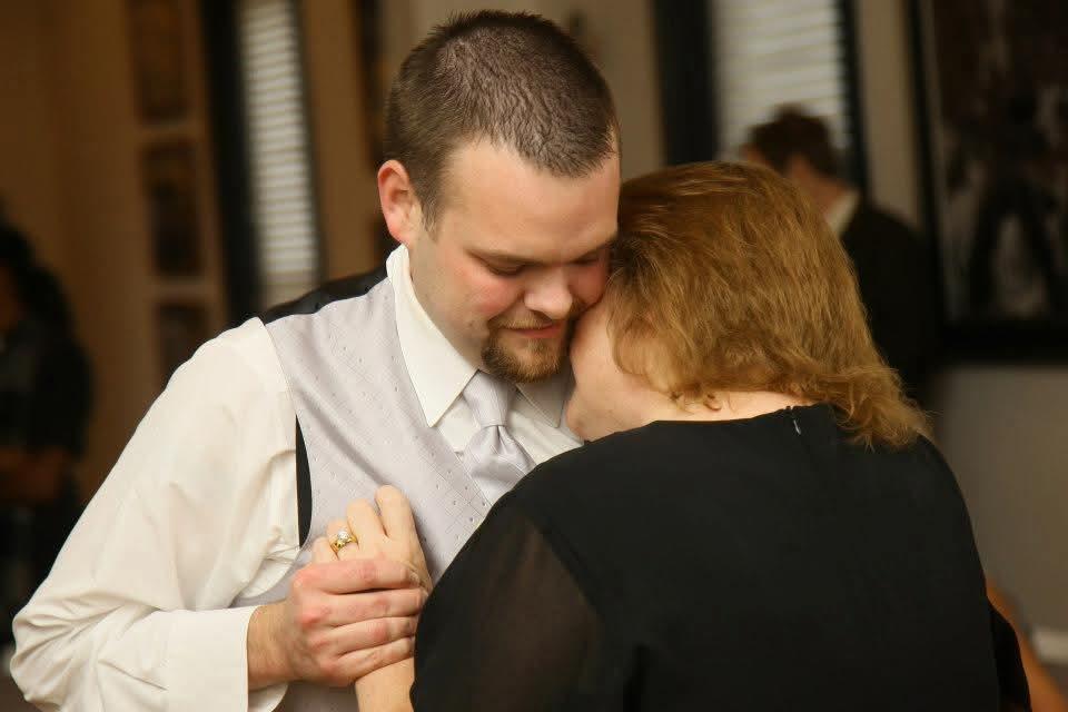 A couple embraces closely while dancing together at a warm gathering.