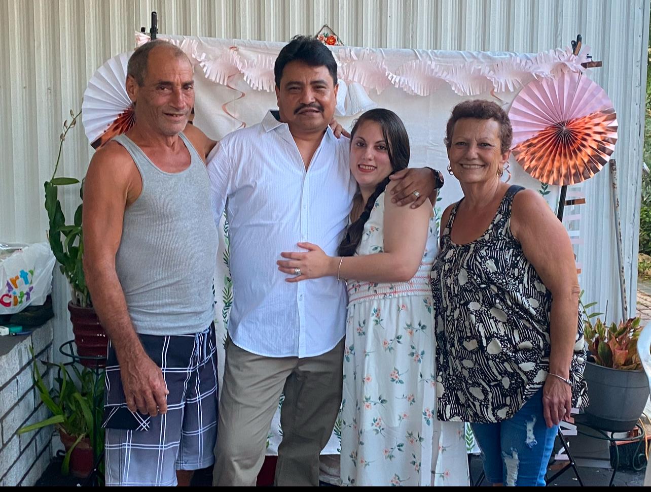 Four family members smile at an outdoor gathering, celebrating their time together.