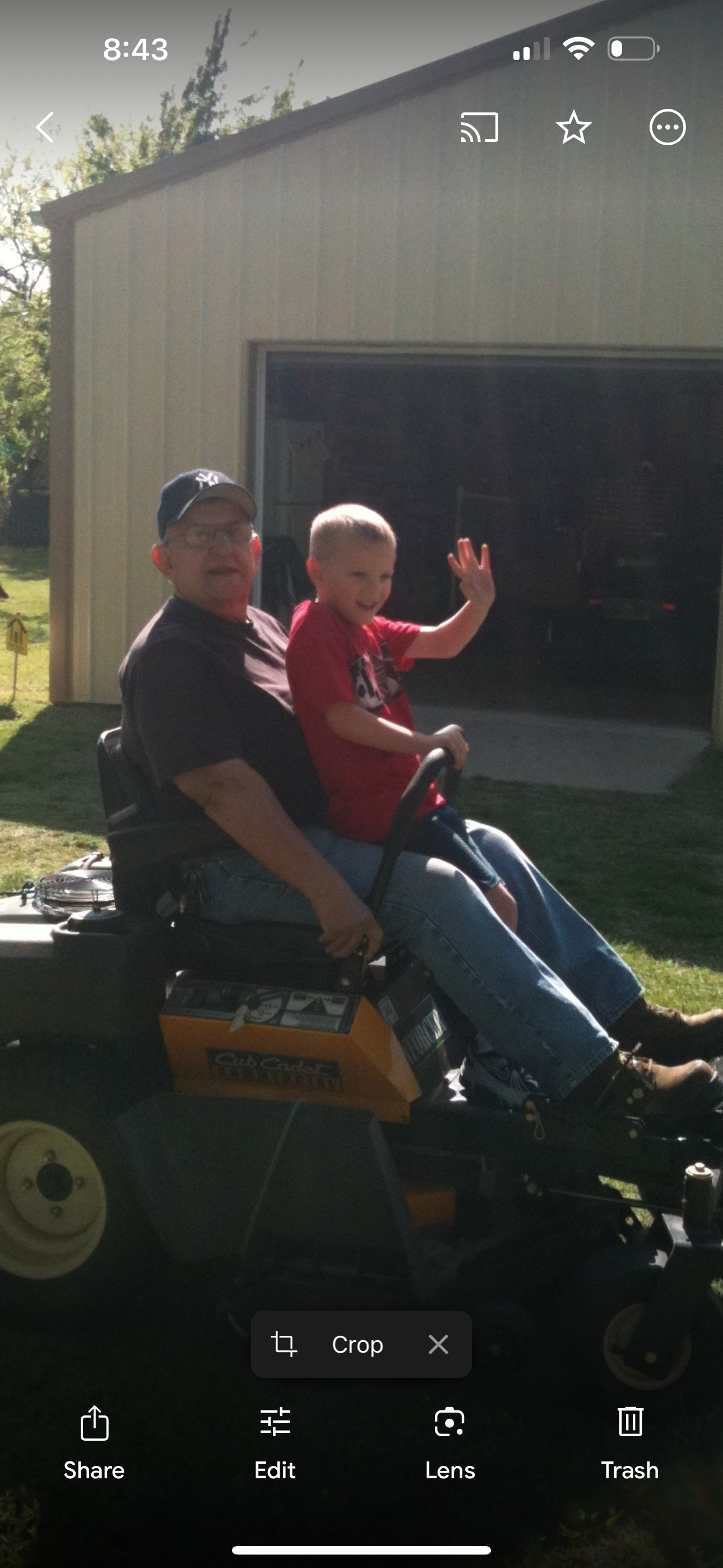 Grandfather and young boy enjoy a fun moment together riding a lawnmower in the yard.