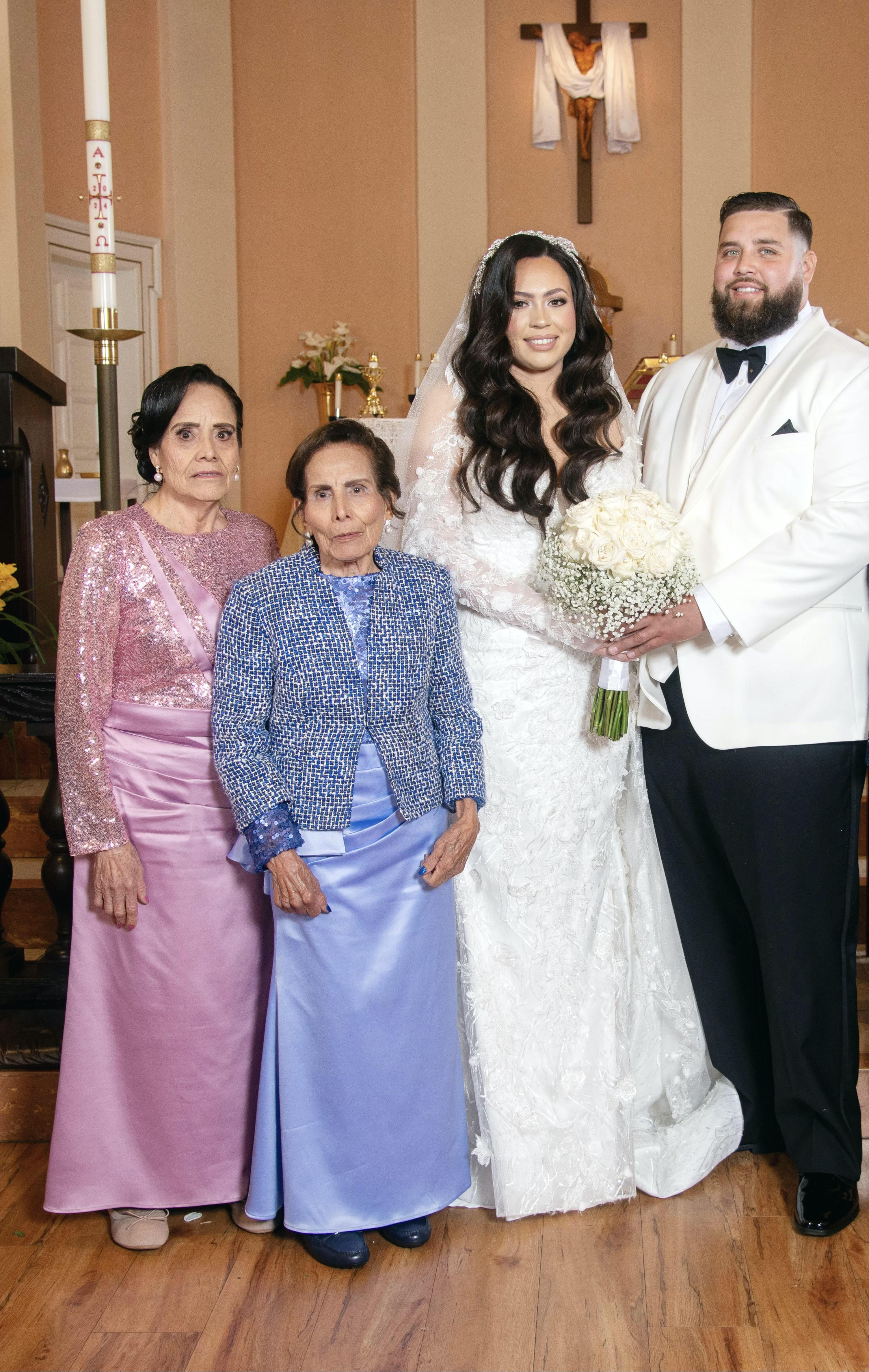Couple celebrates their special day with family, smiling and showcasing wedding attire in a church.