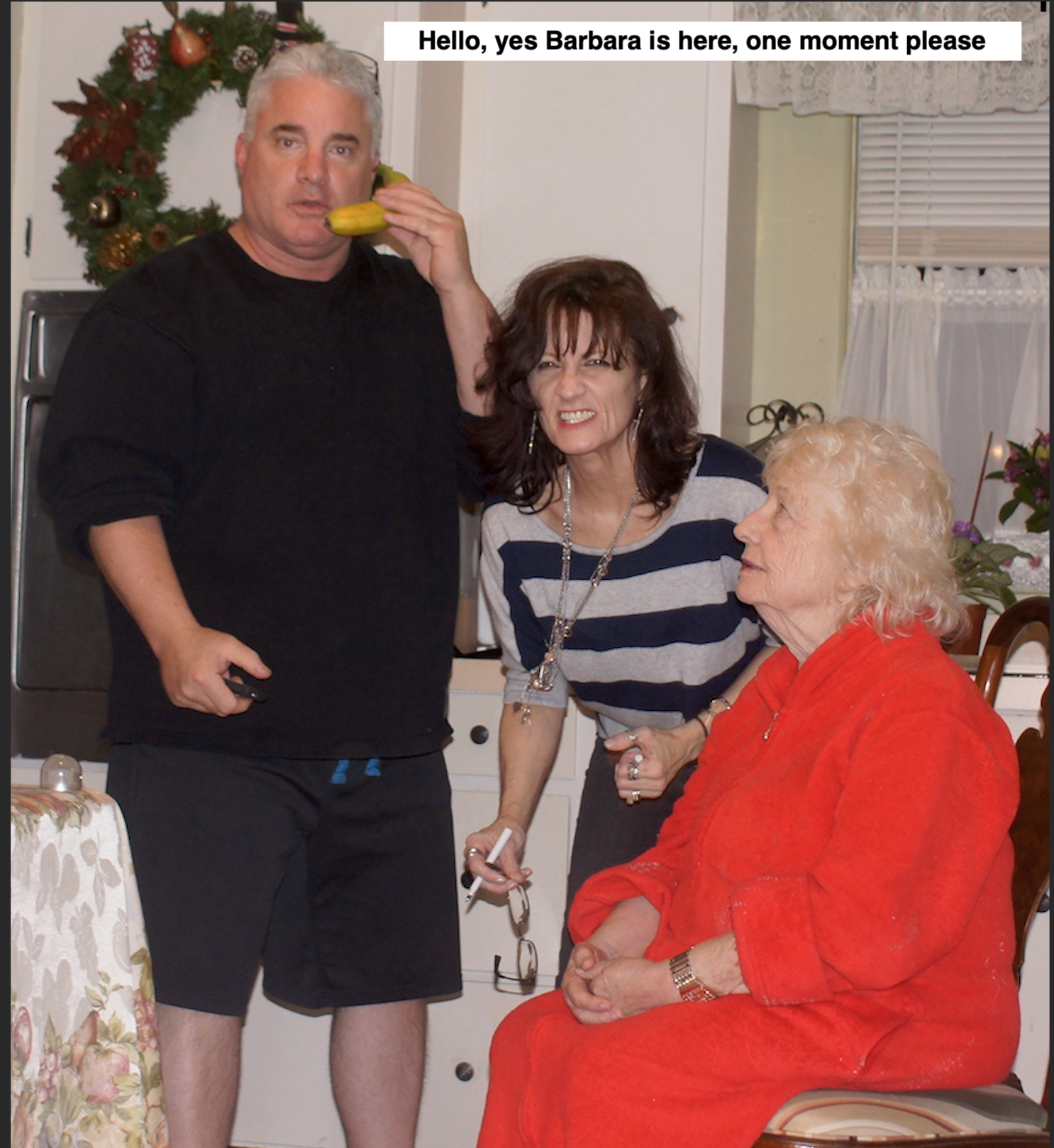 A man talks on the phone while two women smile and engage in lighthearted conversation.