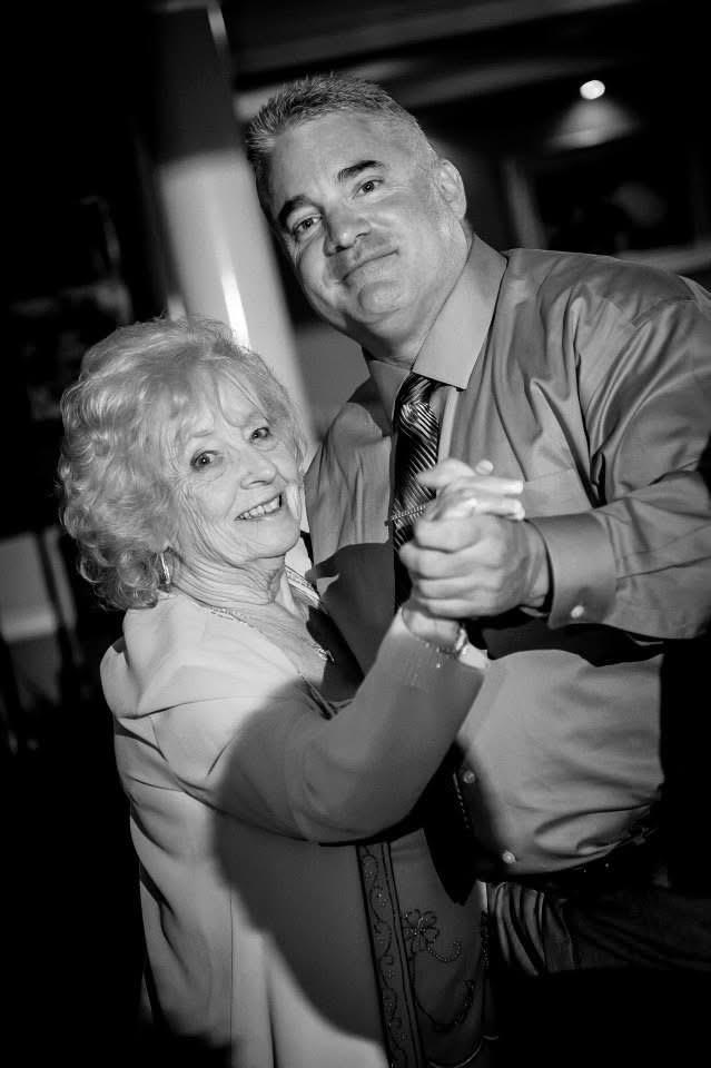 An elderly woman and a man joyfully dance at a festive celebration.