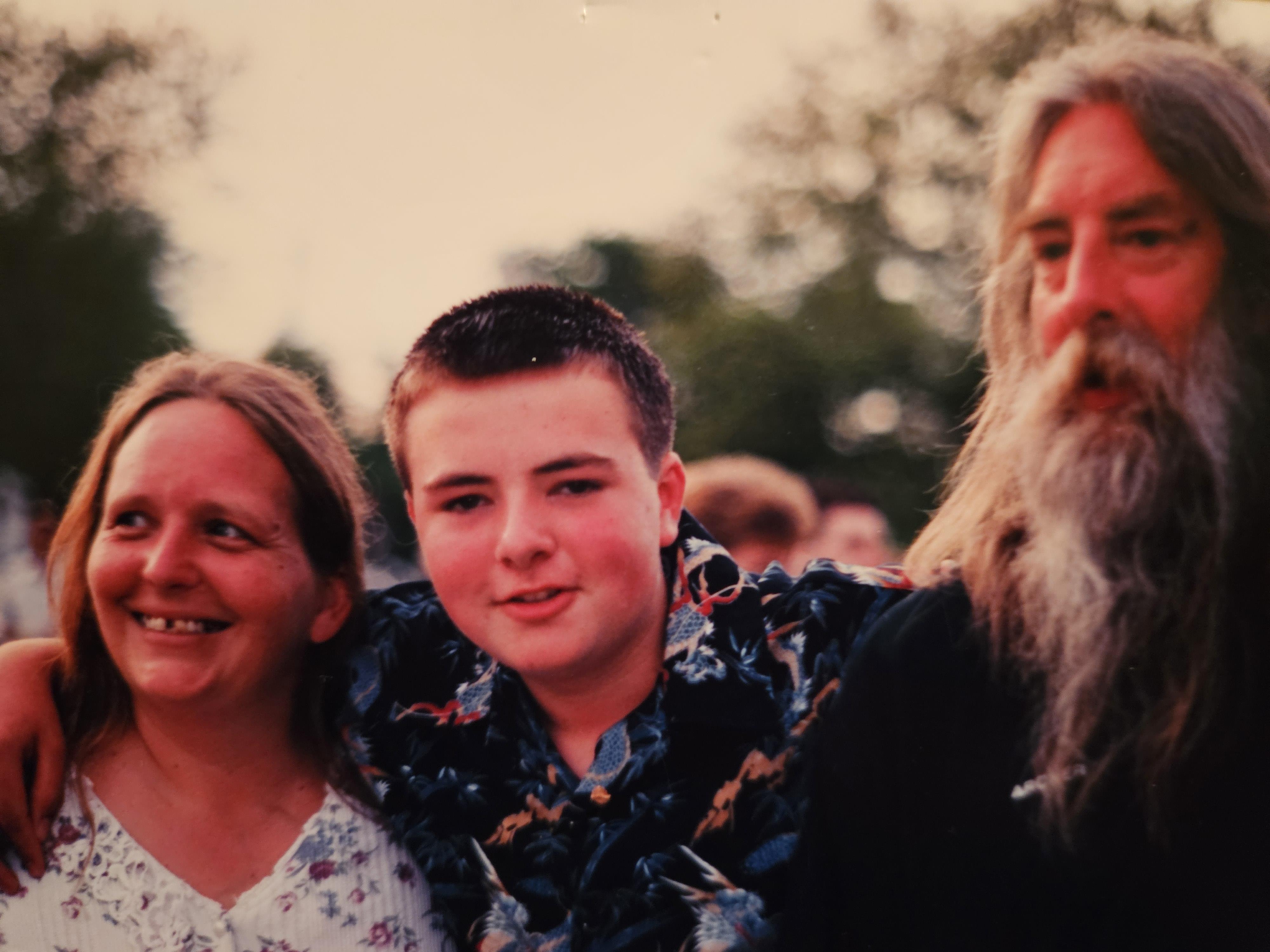 Three people share a warm moment together at a summer event, enjoying each other's company.