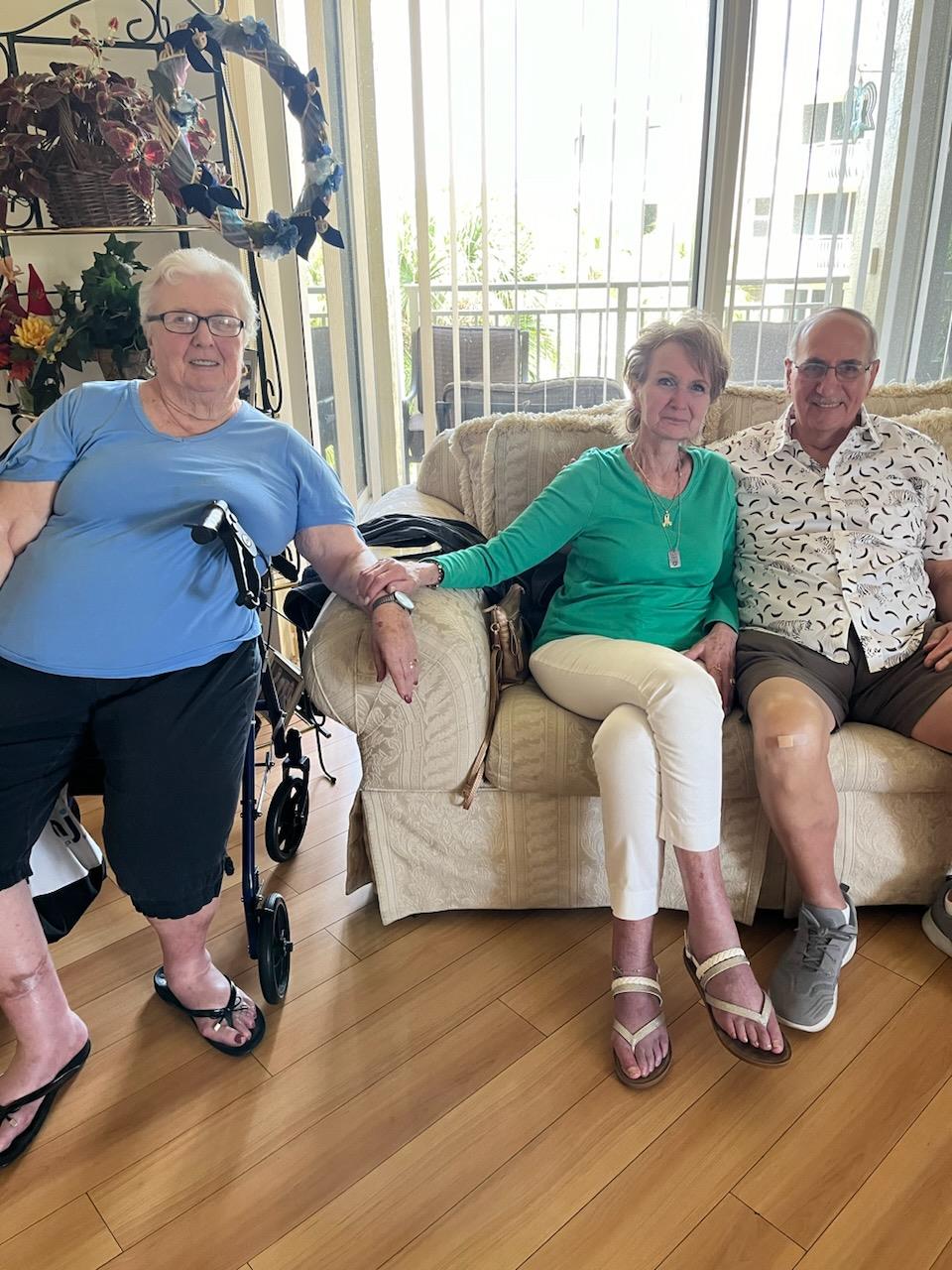Three friends share a light-hearted moment on a couch while enjoying each other's company indoors.