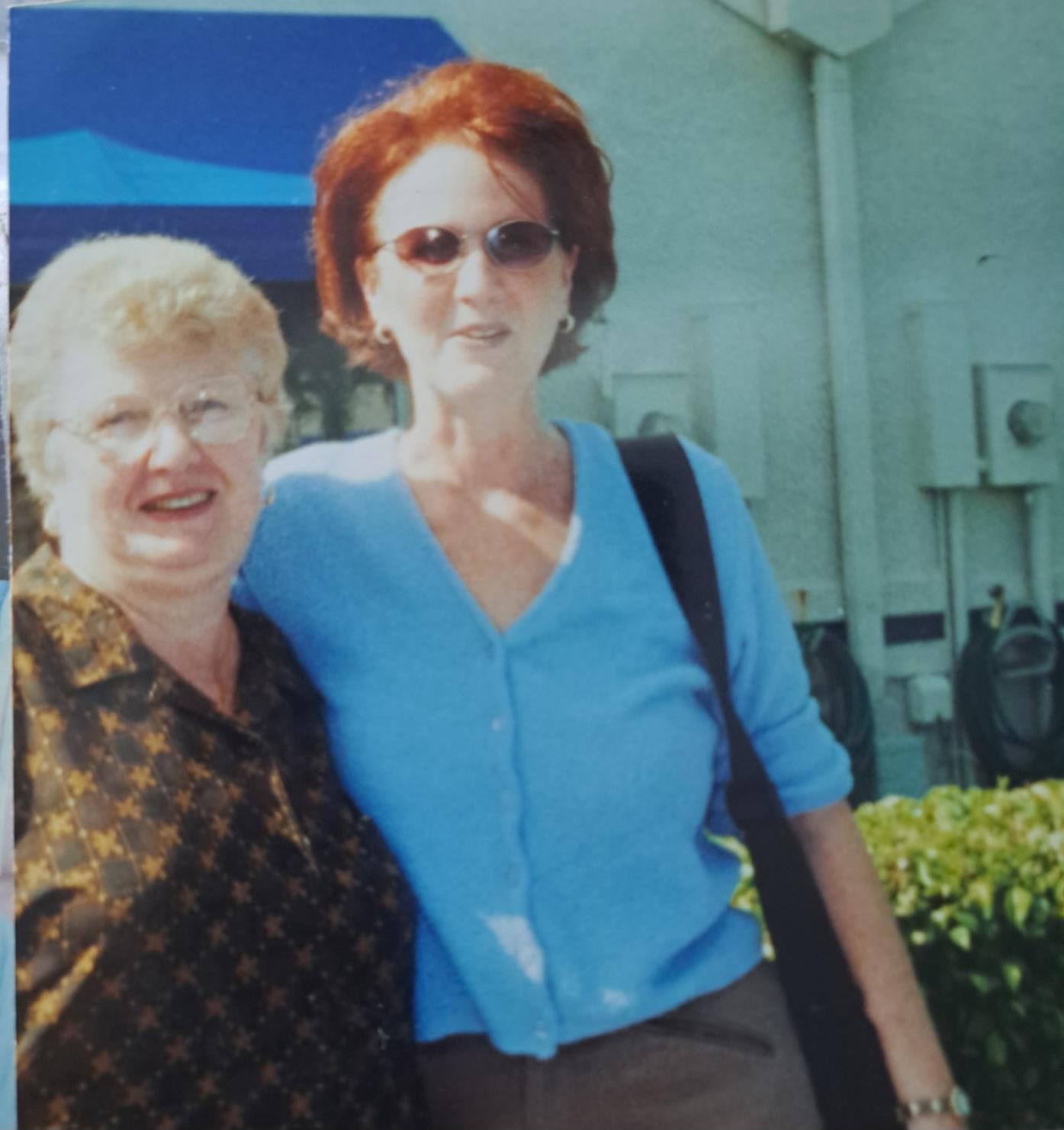 Two friends smile together, enjoying a joyful moment outdoors.