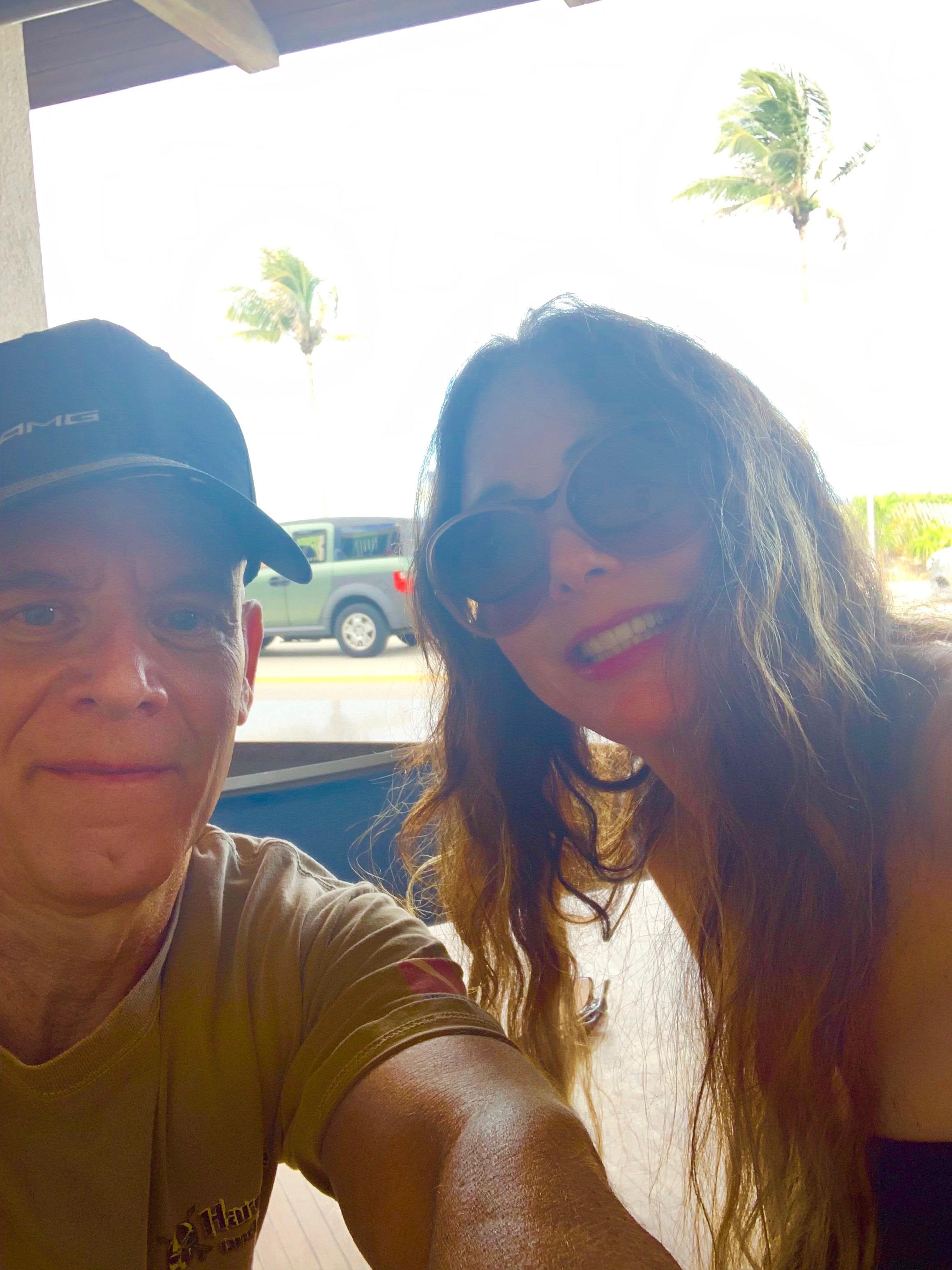 Couple poses happily for a selfie while relaxing outdoors on a sunny day.