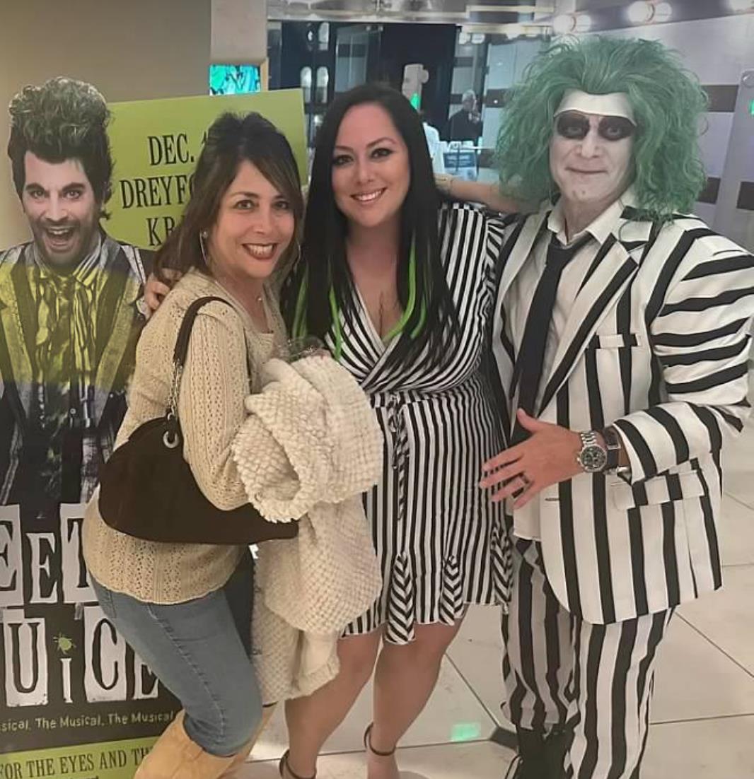 Two friends pose with a character in costume during a lively event at a stylish venue.
