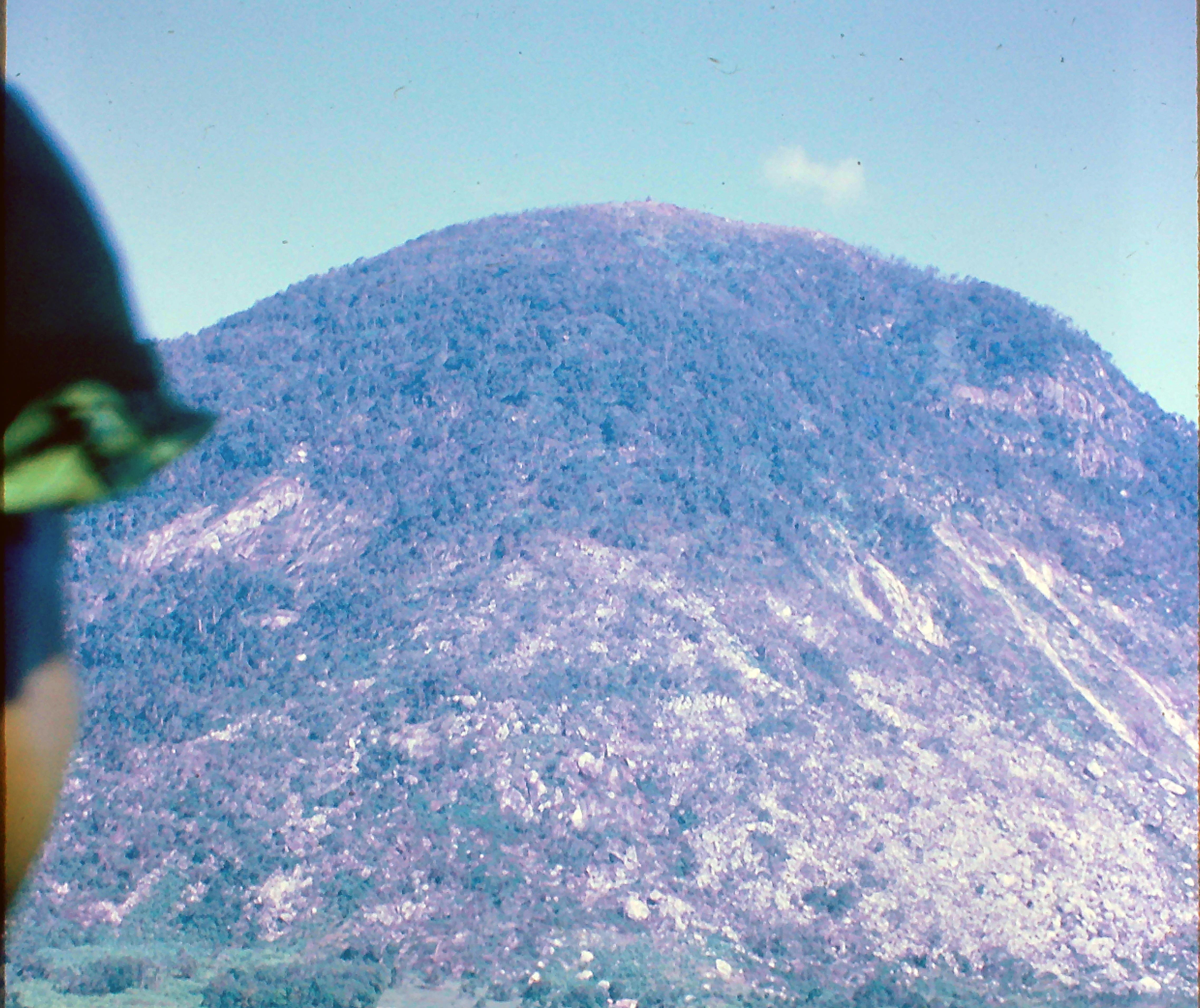 People engage in hiking activities on a mountain while enjoying the sunny weather and views.