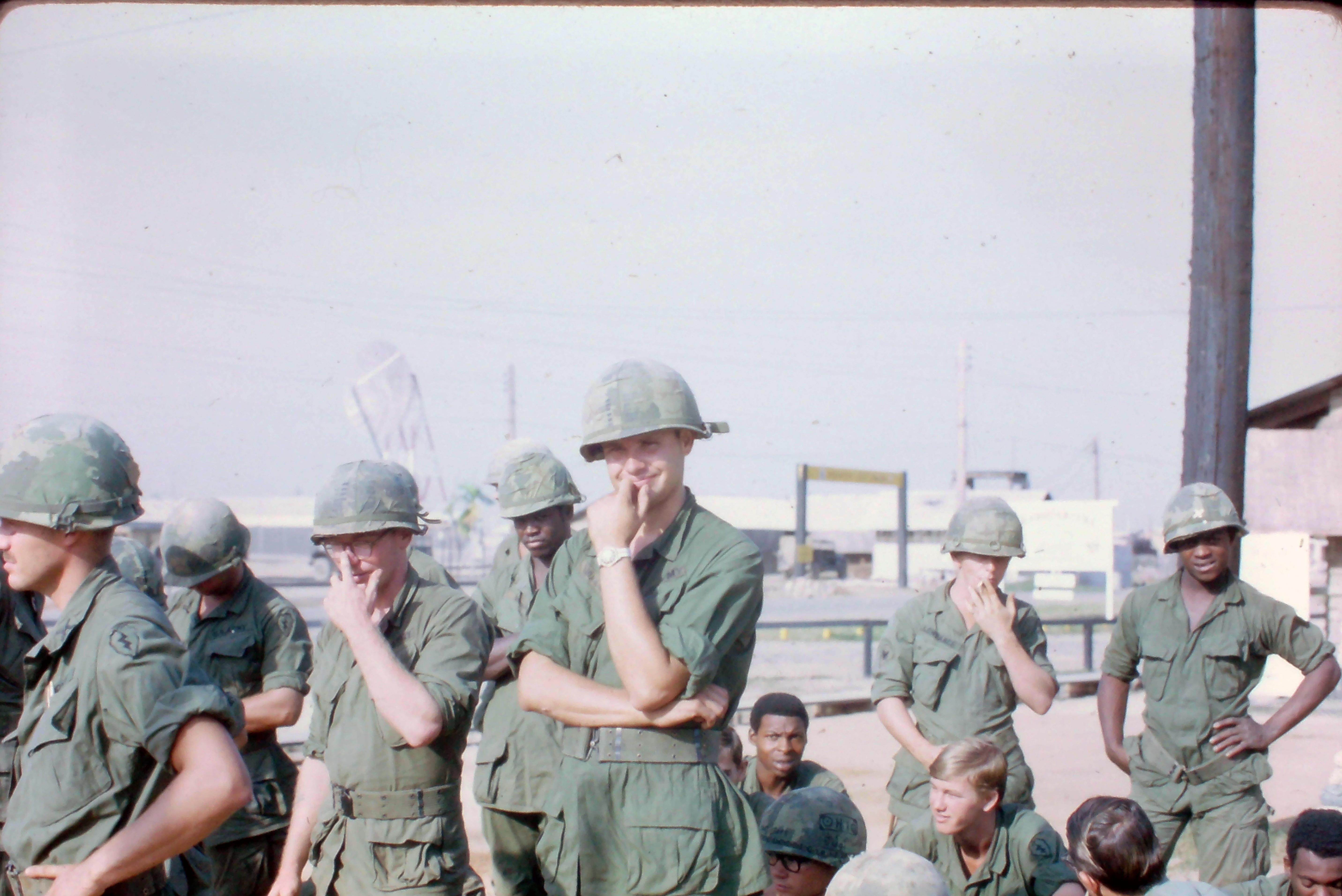 Soldiers dressed in uniforms stand together at a military base, sharing moments and thoughts.