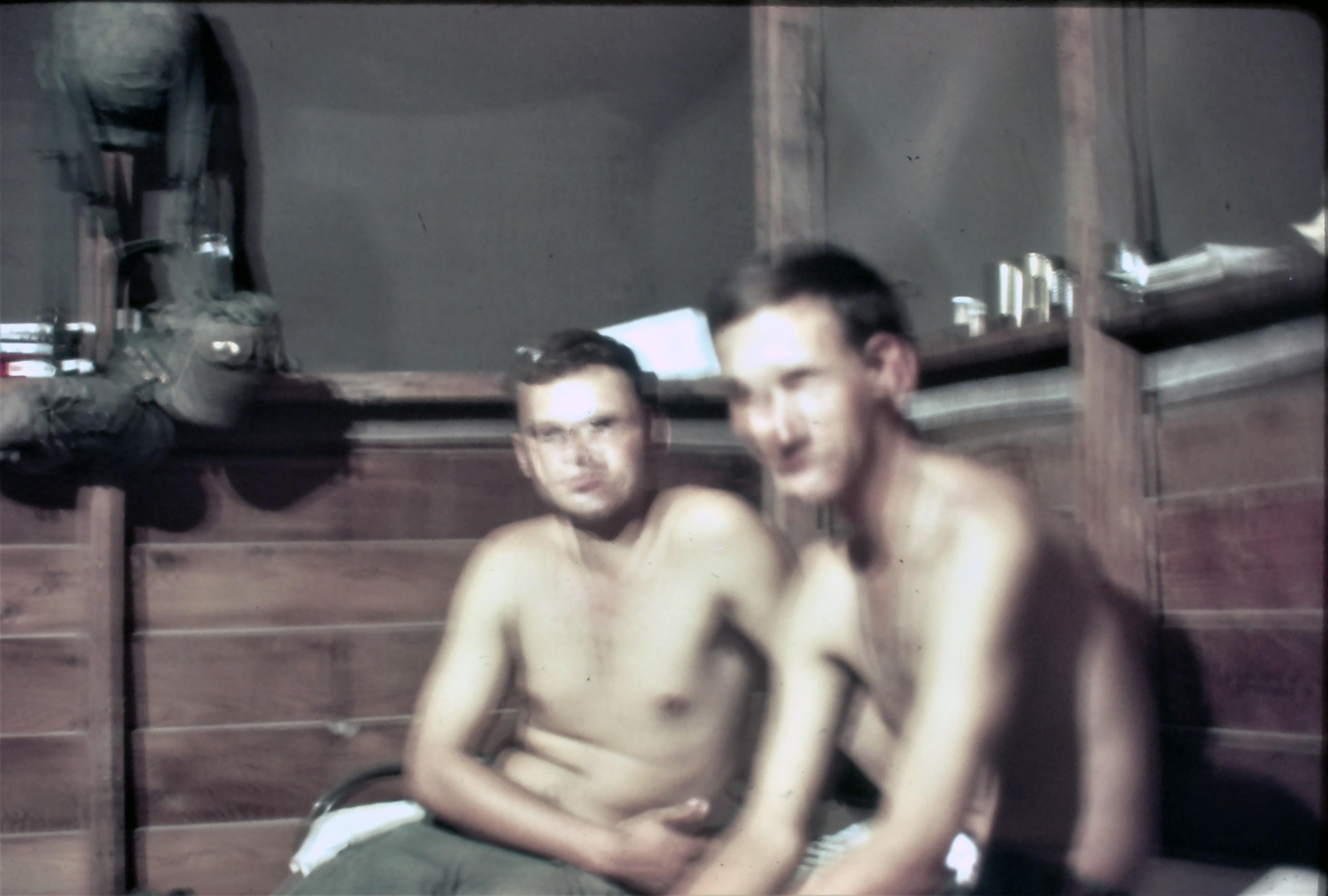 Two men relax in a wooden room, talking quietly and enjoying each other's company in the afternoon.