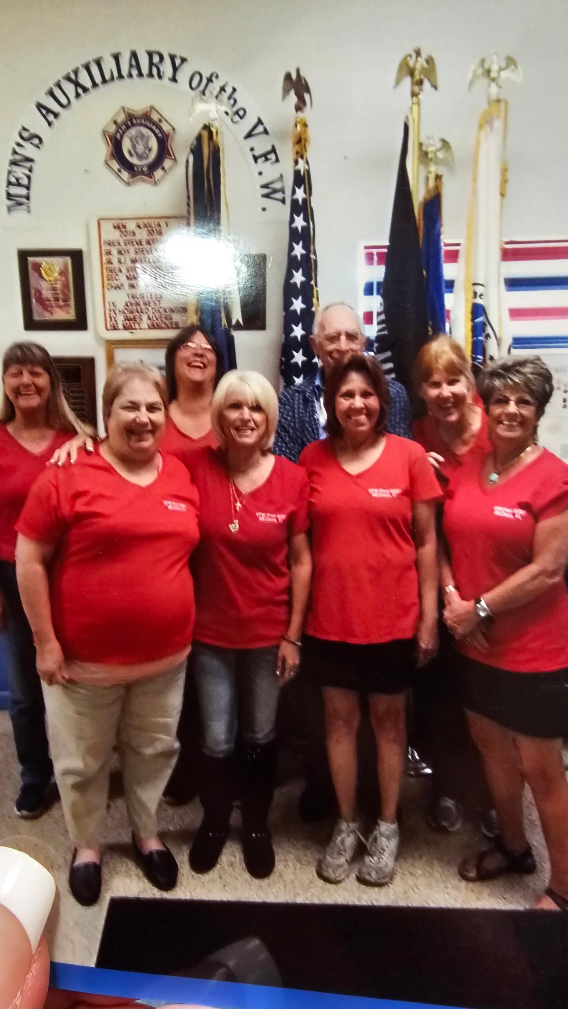 Group of women in red shirts smiling together during a community event at a local center.