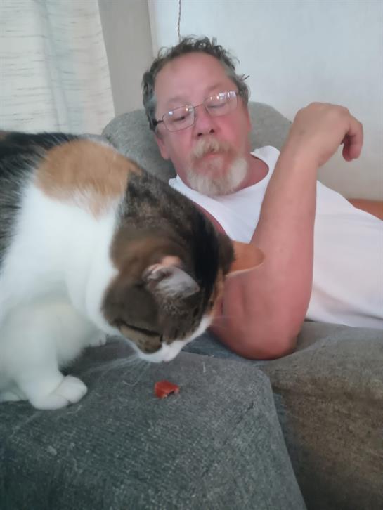 A man lying on a couch with a cat