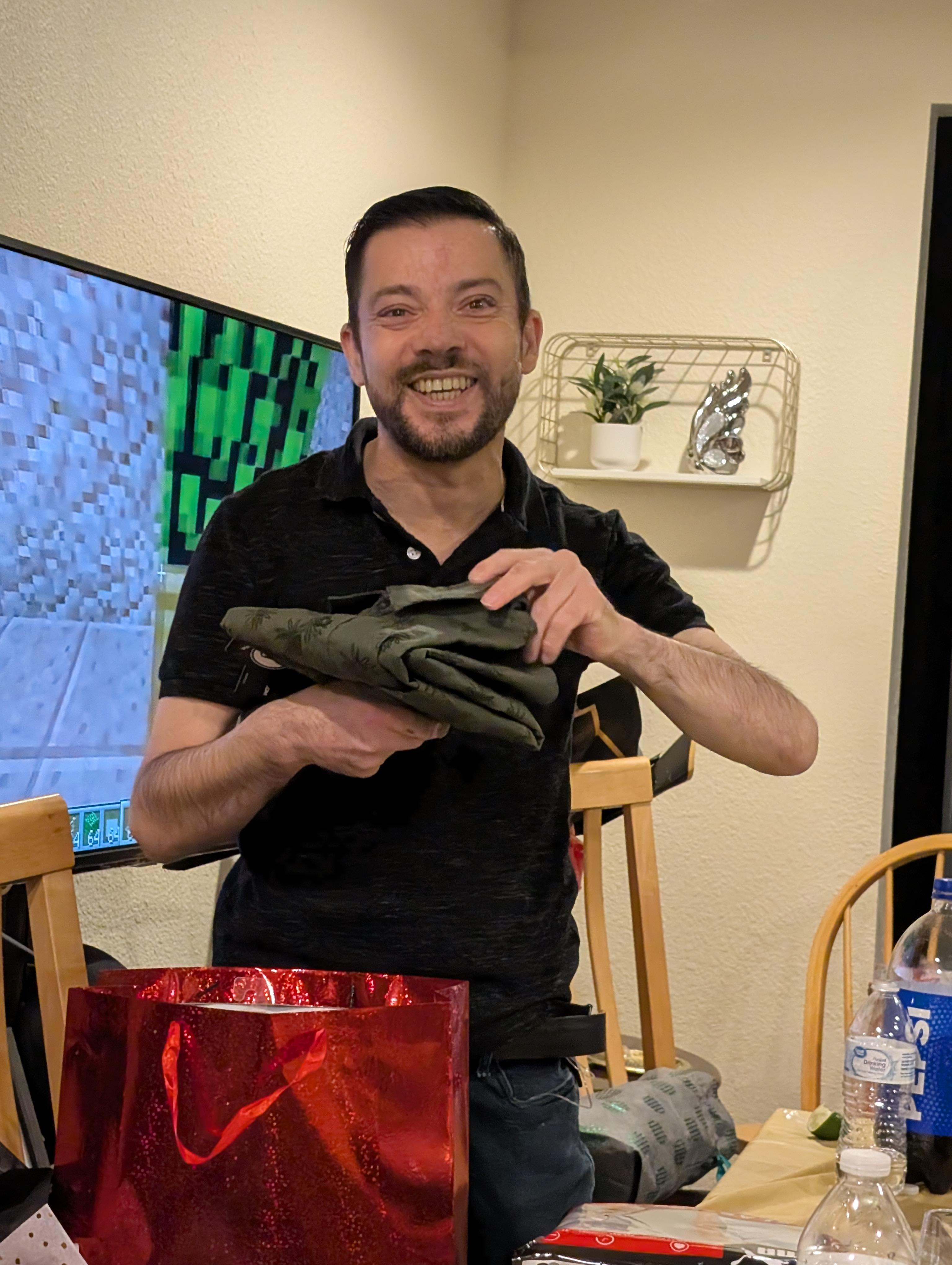 A man displays a folded garment with excitement during a social event with friends at home.