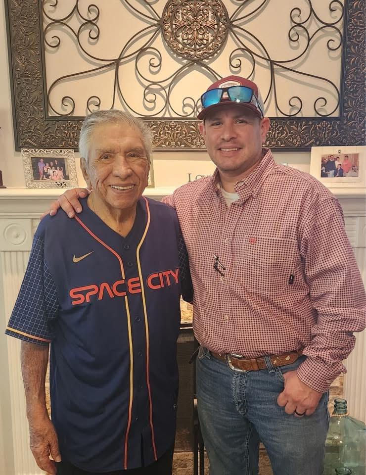 Two men smile together at a family gathering, showcasing warmth and connection in a home.