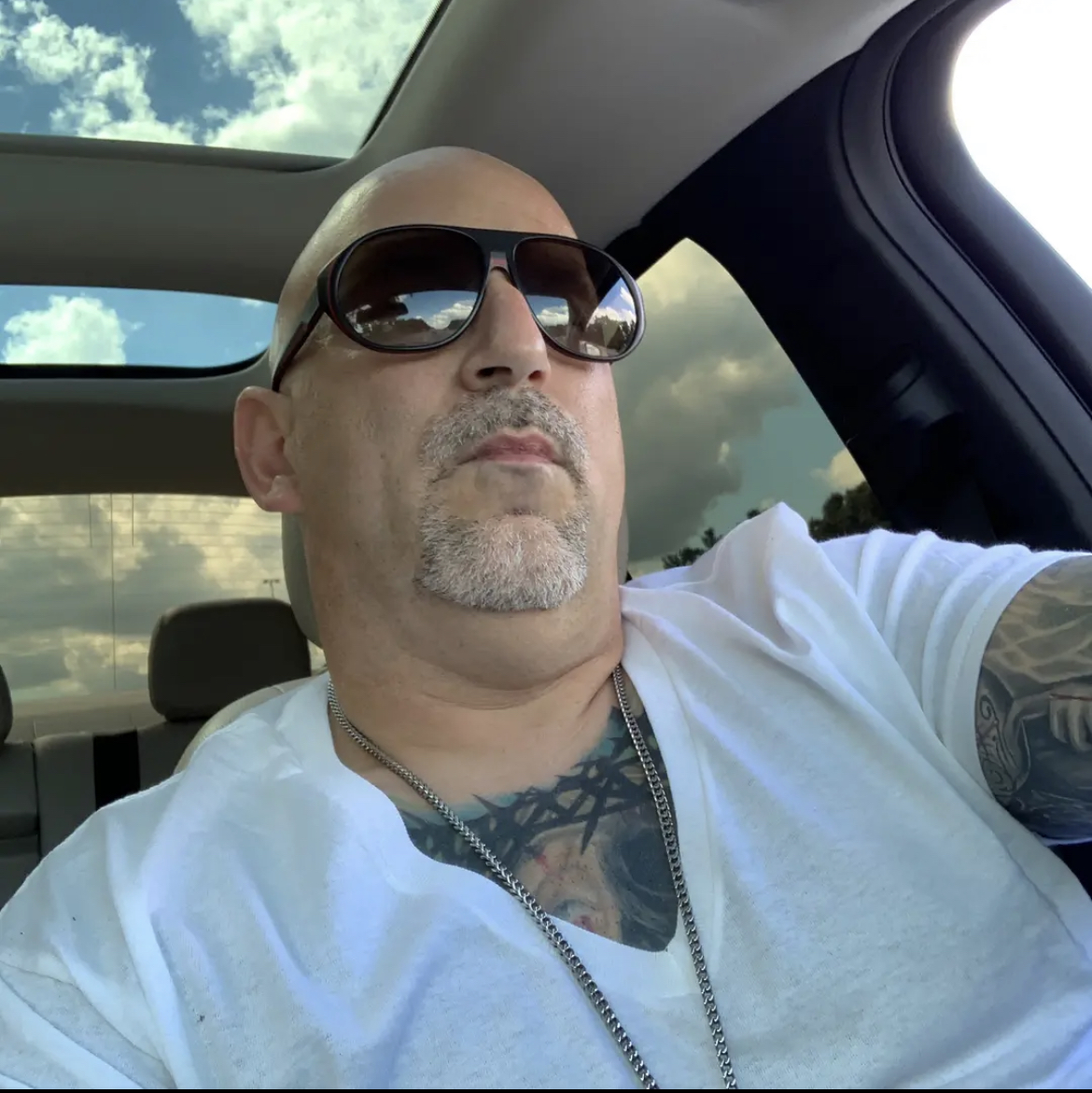 A man wearing sunglasses and a white shirt
