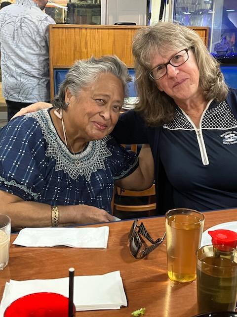 Two friends share a joyful moment at a restaurant, savoring food and drinks during dinner.