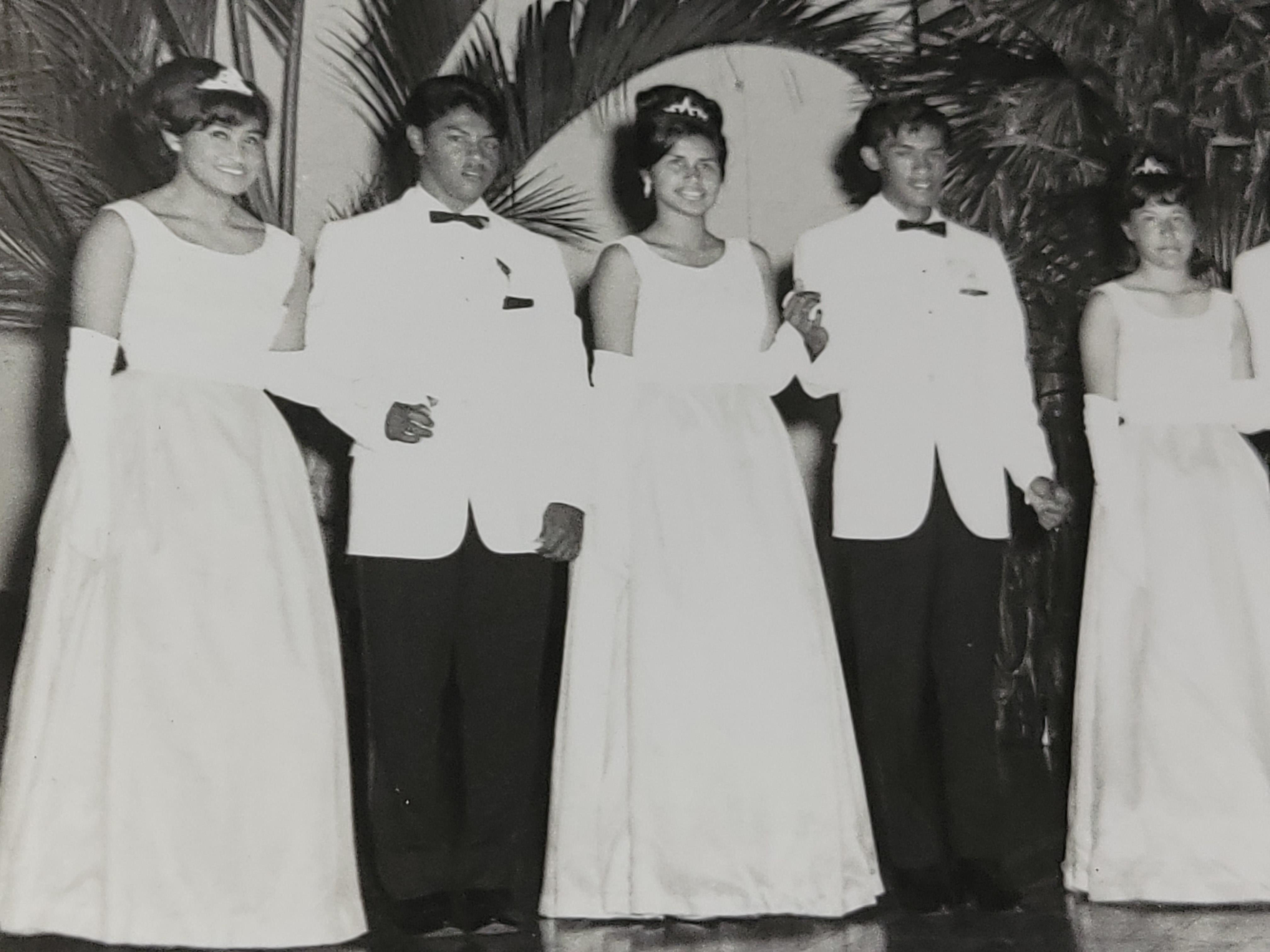 Young adults in formal wear enjoy a dance at an elegant venue filled with decorations.