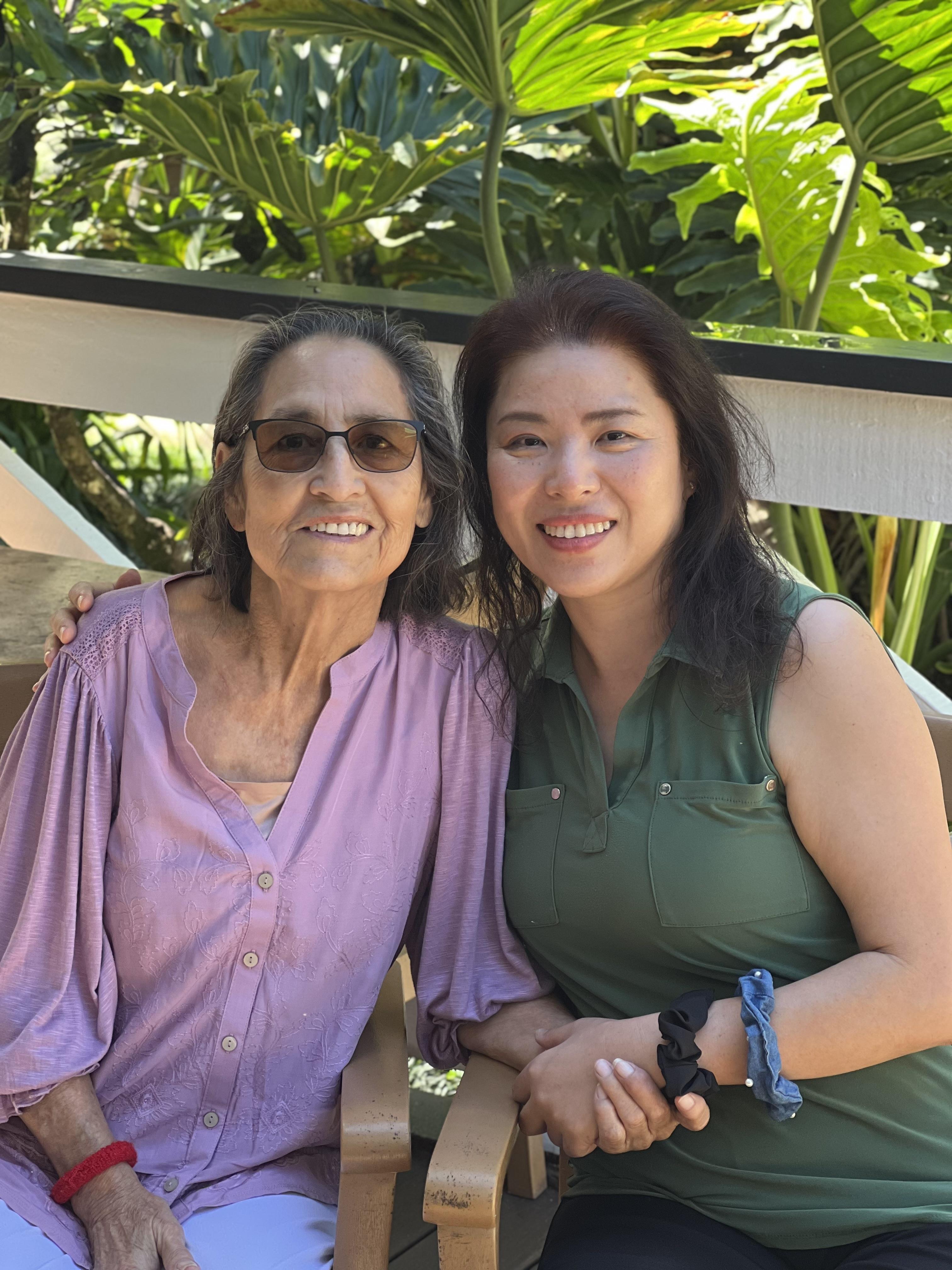 Two women enjoy each other's company in a vibrant garden filled with greenery.