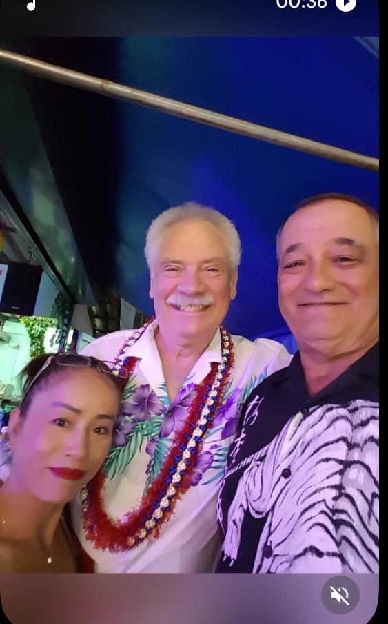 Three individuals smile together while celebrating at a lively event, showcasing bright decorations.