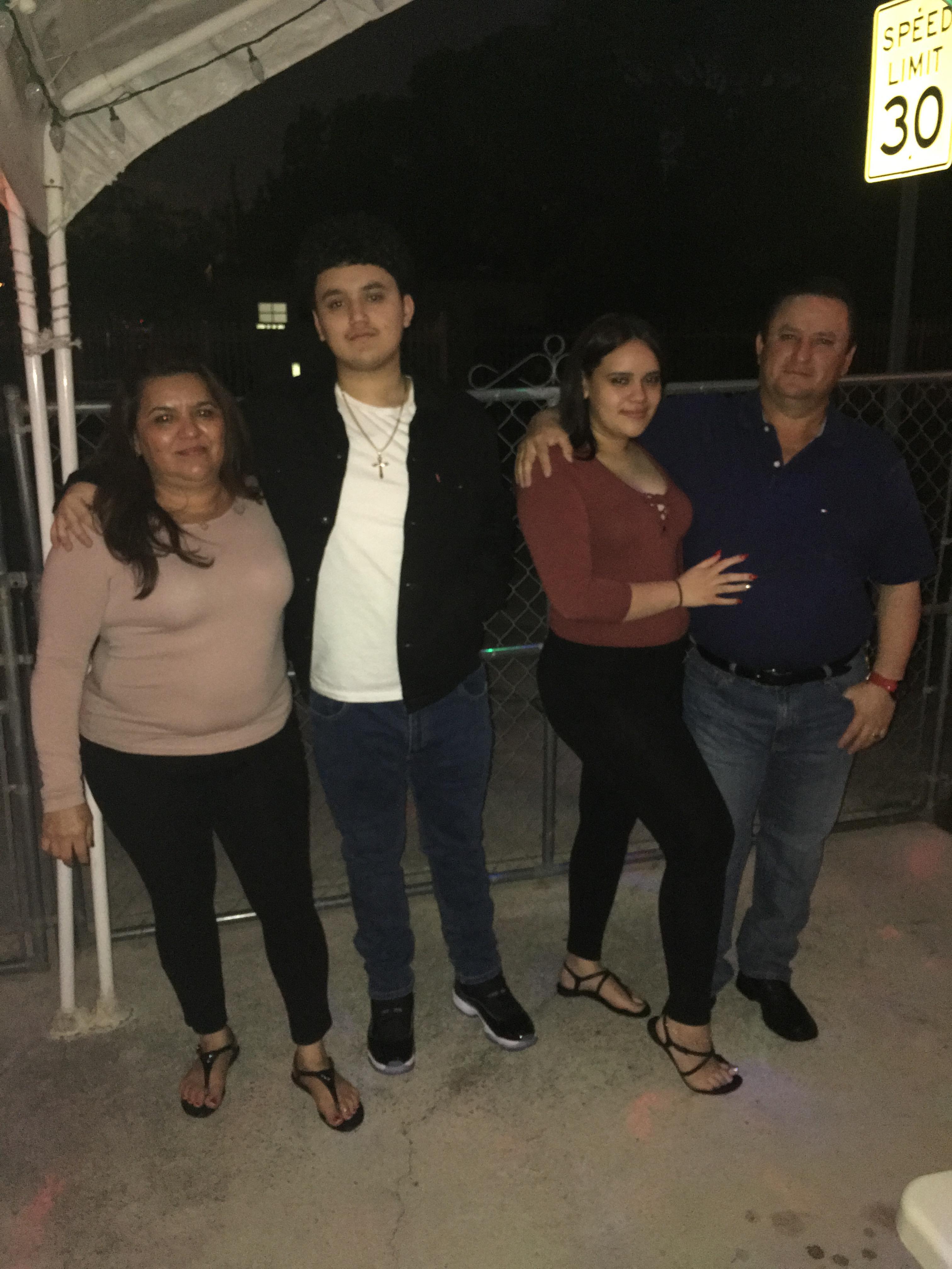 Family members pose together outdoors at dusk, enjoying the moment in front of a fence.