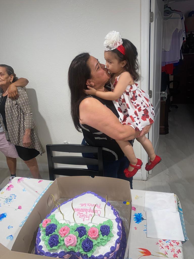 A grandmother and granddaughter share a loving birthday moment in a cozy home.
