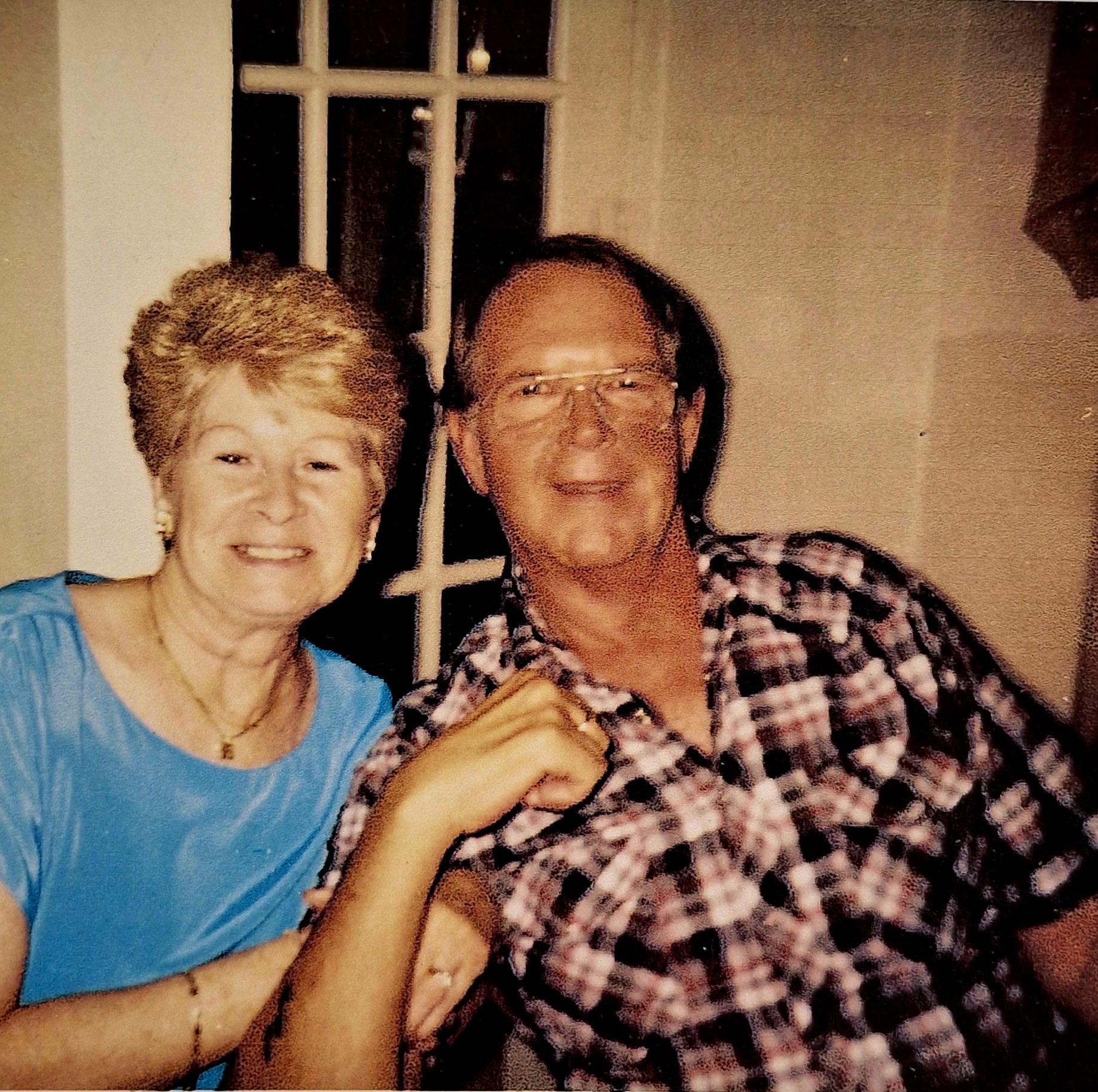 A happy couple smiles together during a family gathering in a warm and inviting home atmosphere.