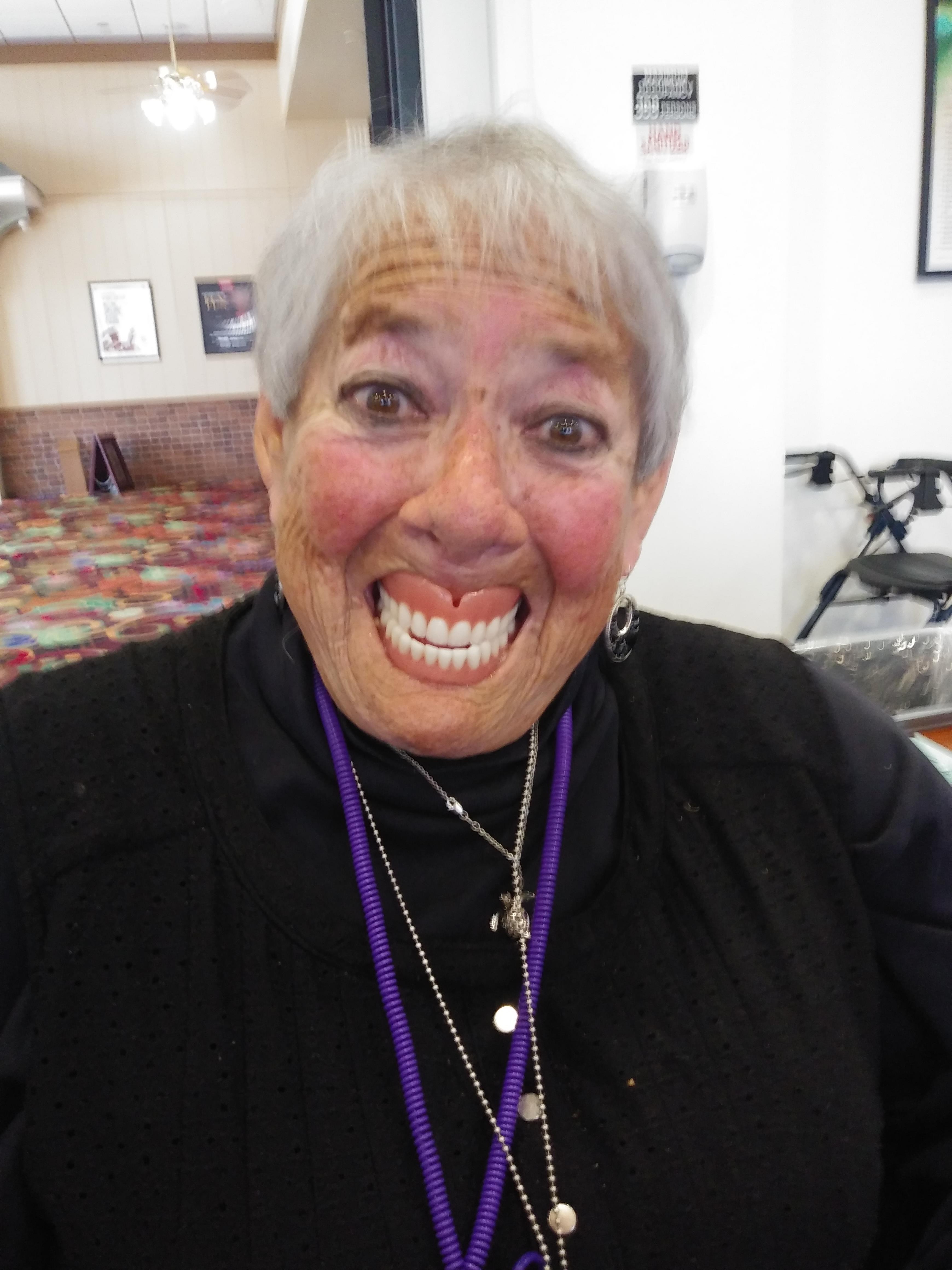A lively elderly woman shows her joyful smile while chatting at a community gathering.