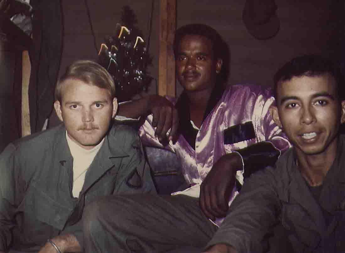 Three soldiers relax in a barrack, dressed in military attire while celebrating during the holiday.
