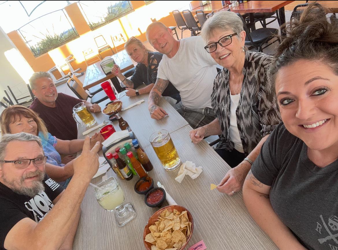 Friends gather at a table, laughing and sharing drinks and snacks in a restaurant.
