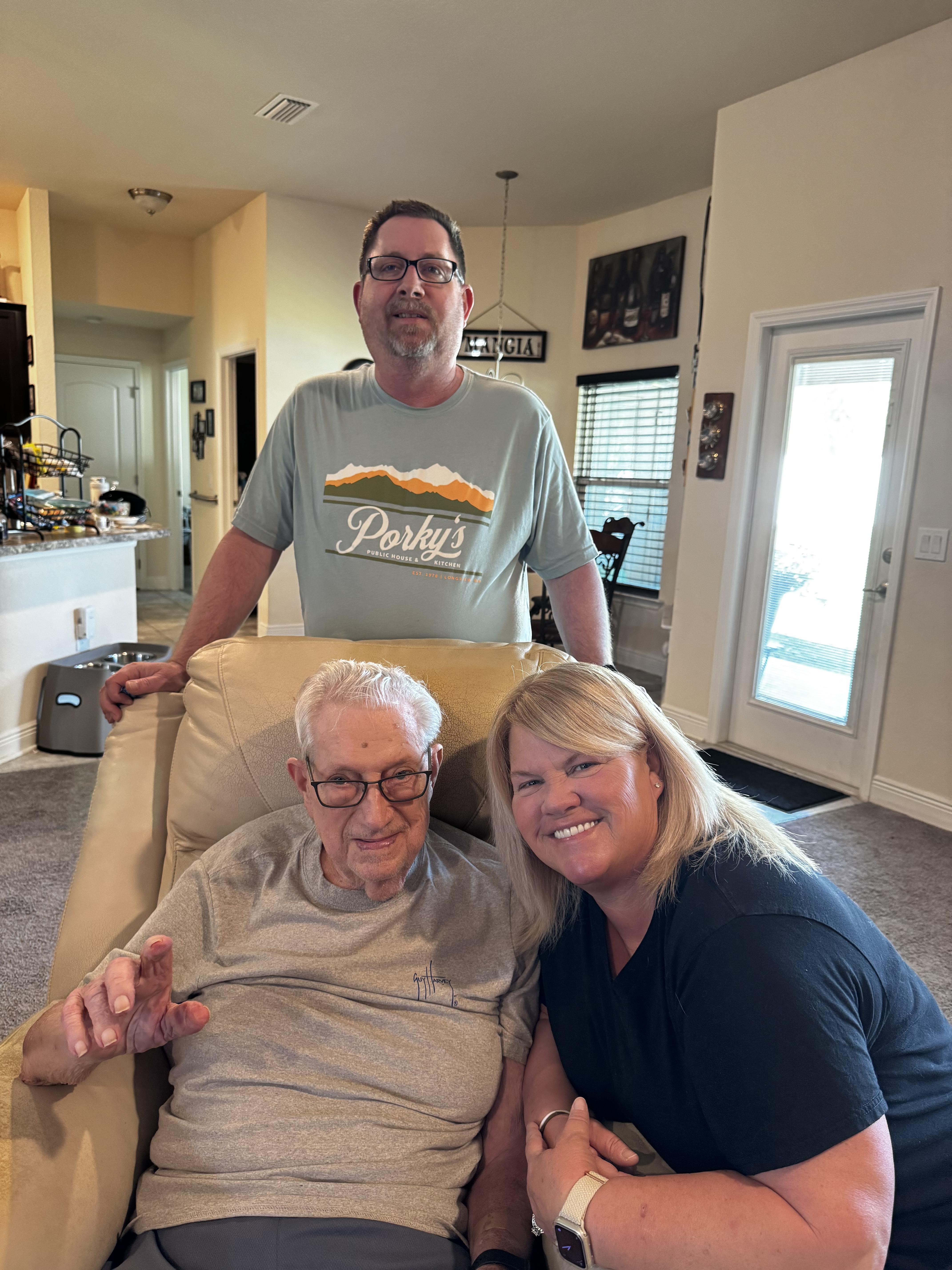 Three family members share a cheerful moment together in a cozy living room setting.