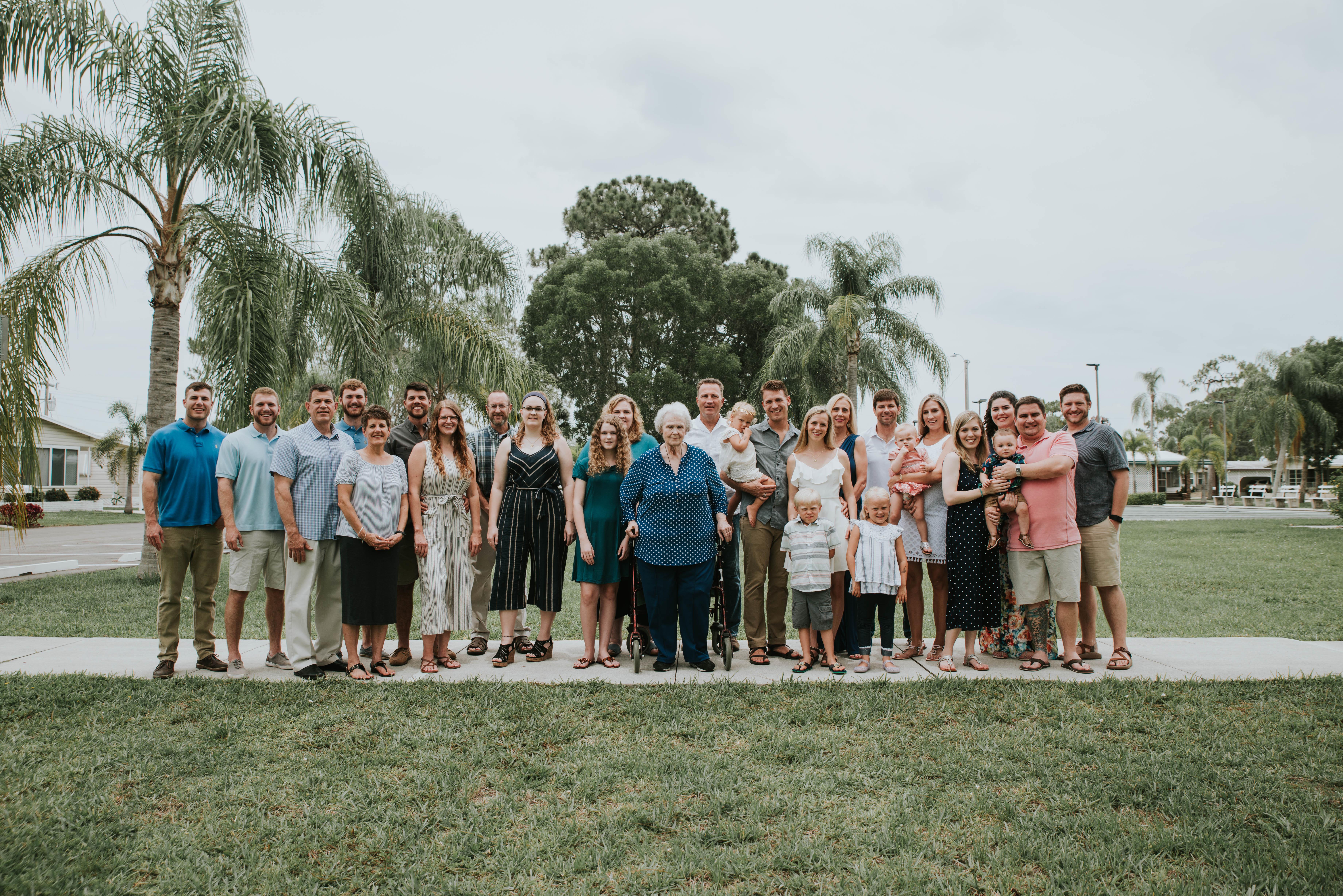 A large extended family poses together in a park, showcasing smiles and close relationships.
