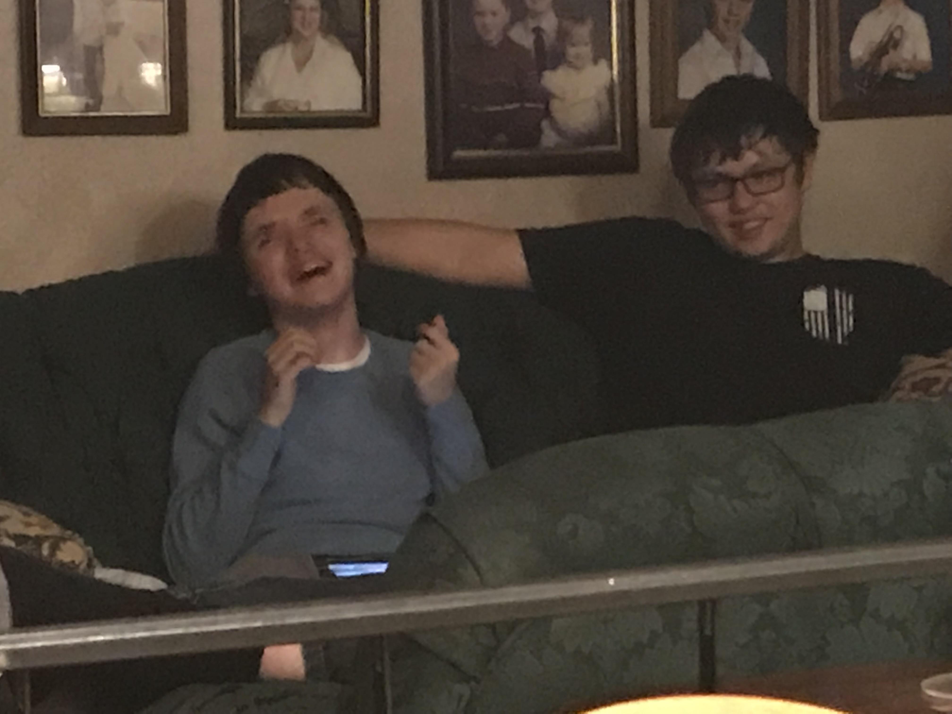 Friends share laughter and good times while sitting on a couch amid family memories.