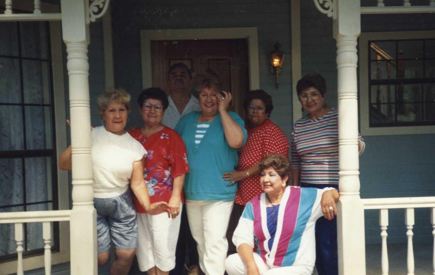 Friends gather on the porch for a joyful summer reunion, sharing smiles and laughter together.