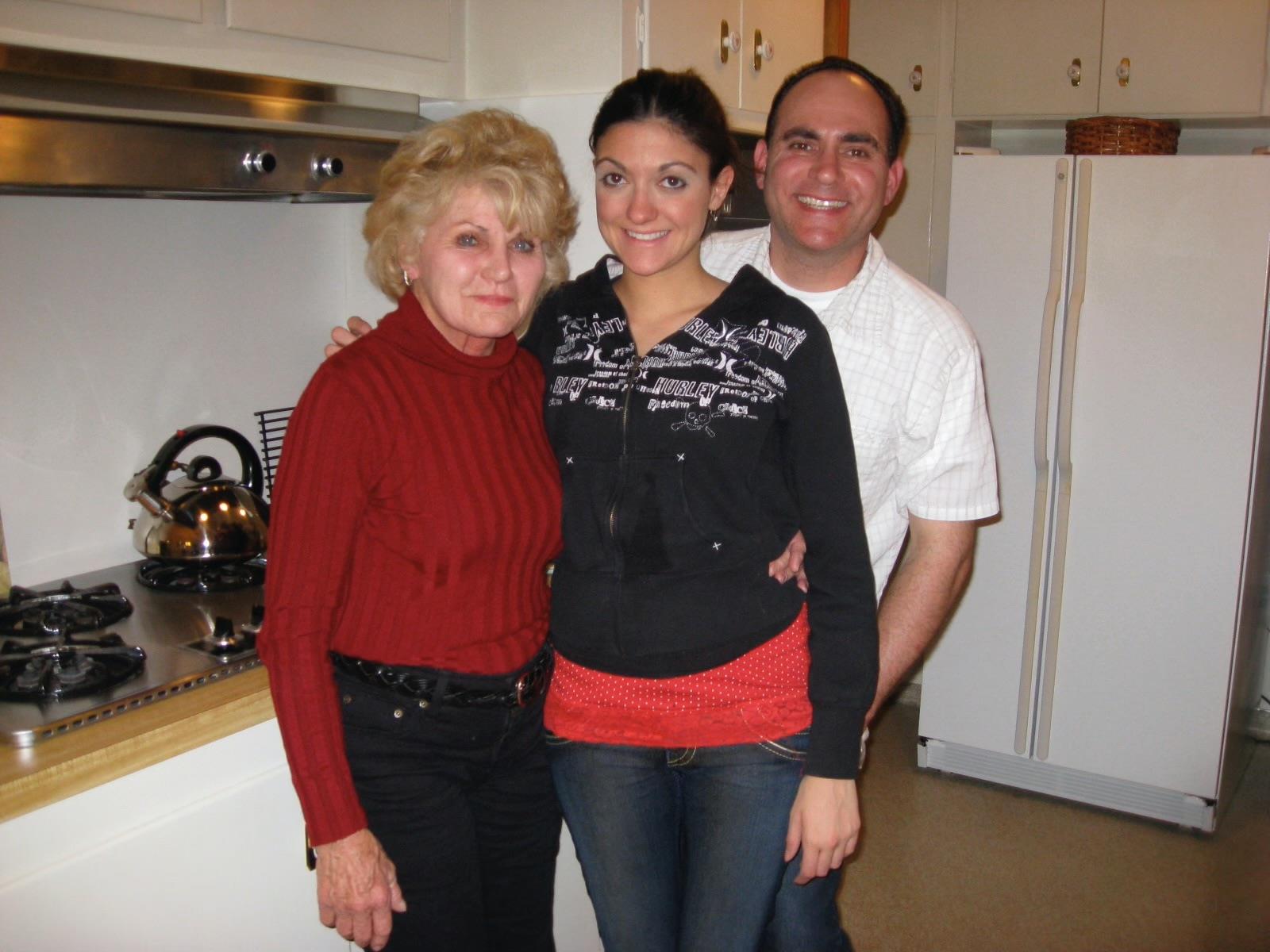 Three people pose happily in a warm kitchen, enjoying a delightful family moment together.