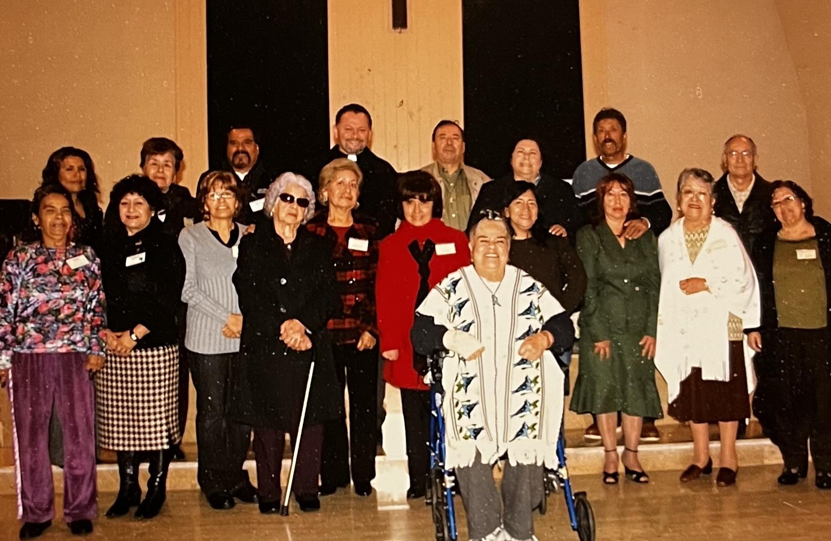 A gathering of seniors poses together indoors, showcasing joy and camaraderie among friends.