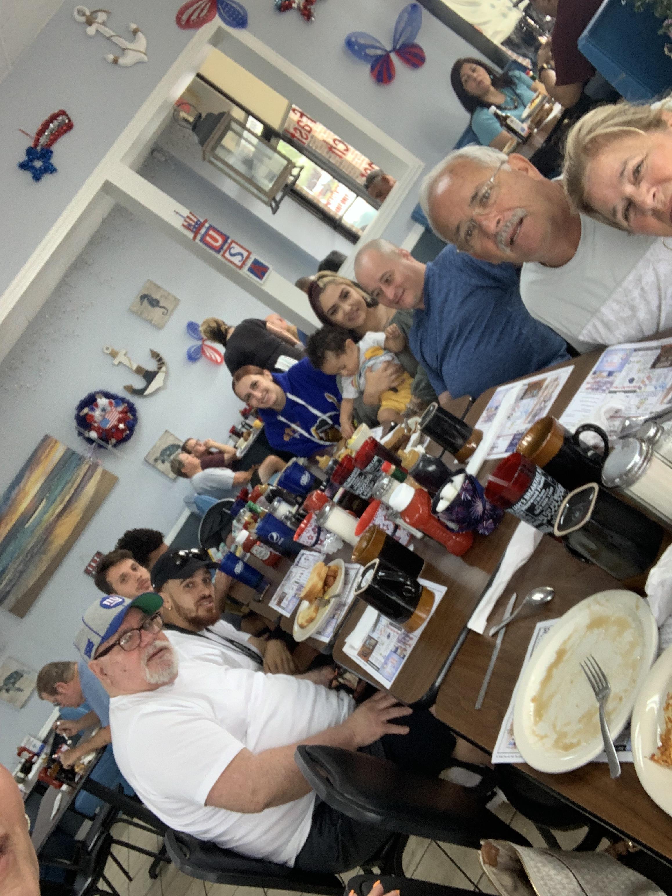 A large family enjoys a delicious meal at a vibrant restaurant filled with lively decor.