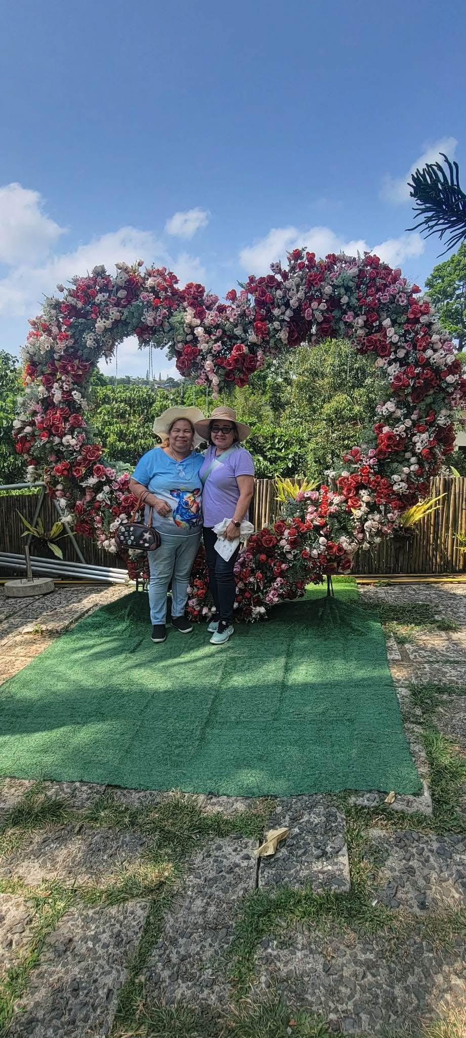 Friends celebrate their bond together in a joyful moment surrounded by vibrant flowers.