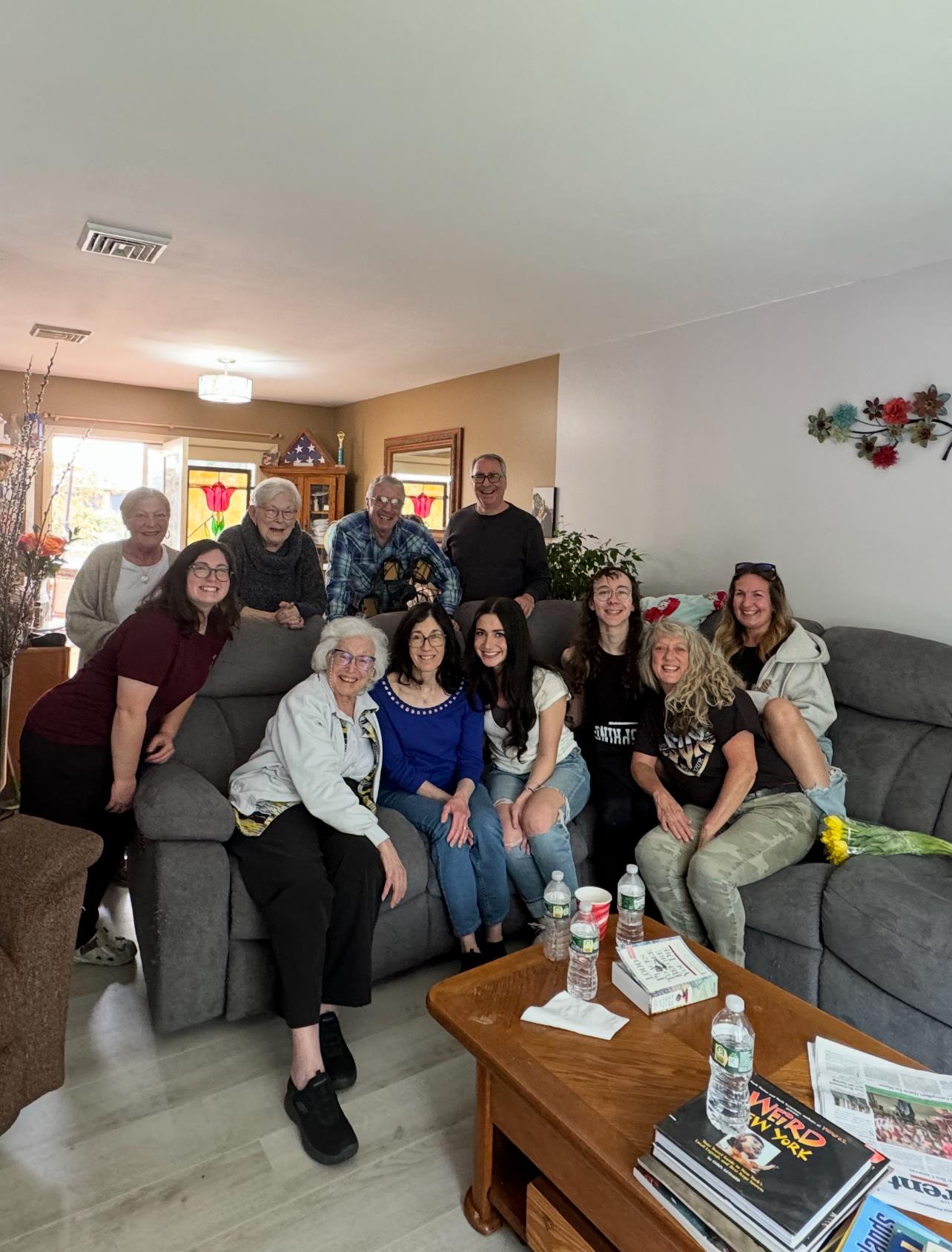 A happy group of friends and family gathers in a cozy living room, sharing smiles and laughter.