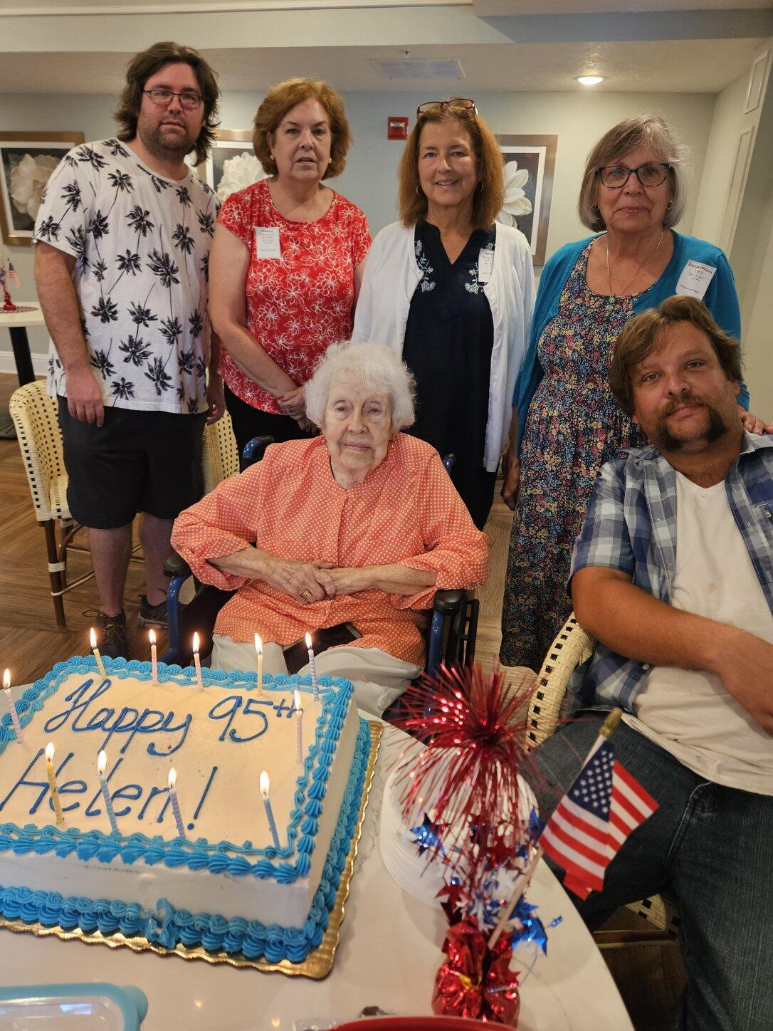 A family gathers to celebrate a 95th birthday, surrounded by cake, smiles, and decorations.