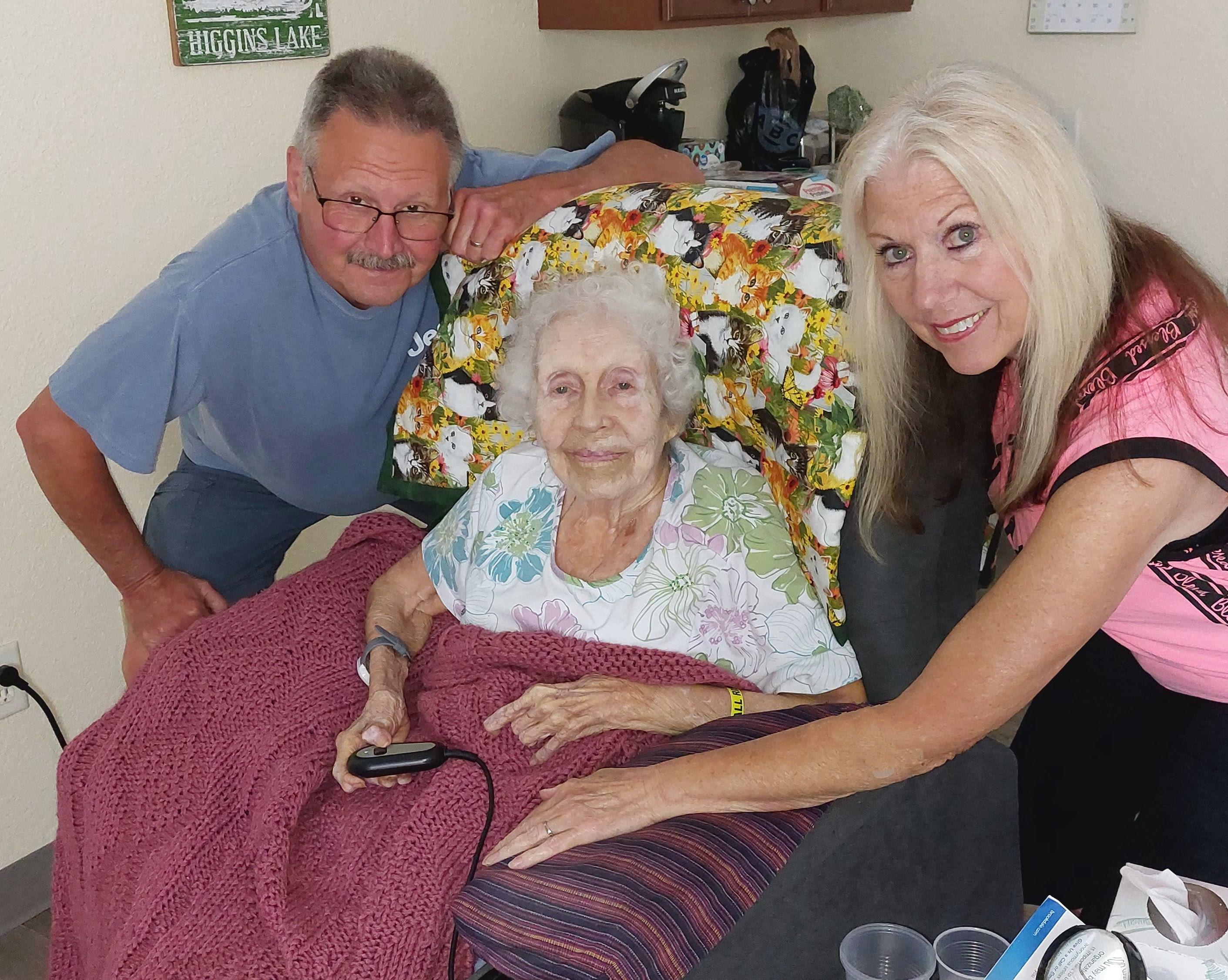 Family gathers around a joyful elderly woman in a comfortable living room filled with love.