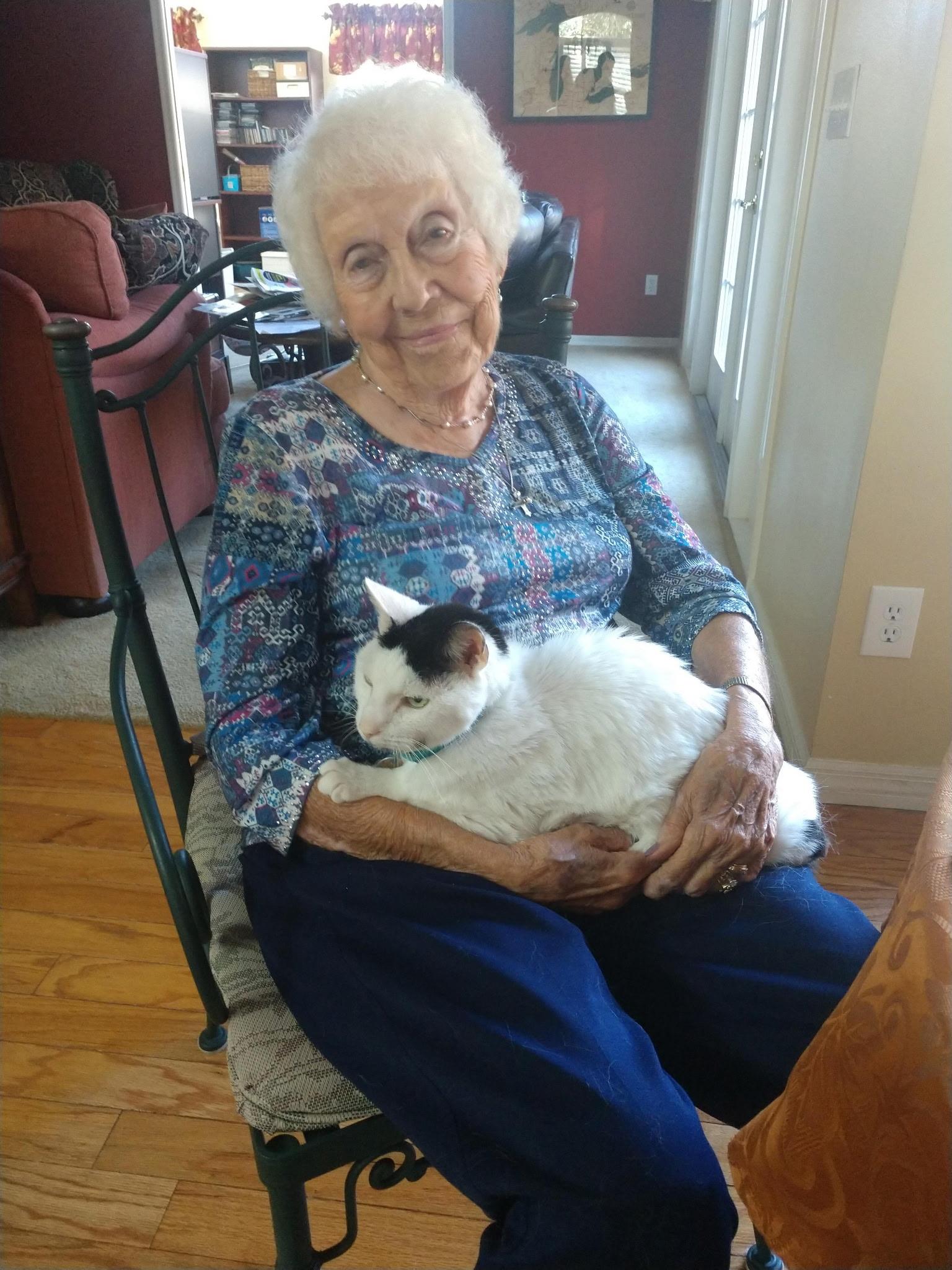 An older woman spends peaceful moments holding her sleeping cat in a homey living space.