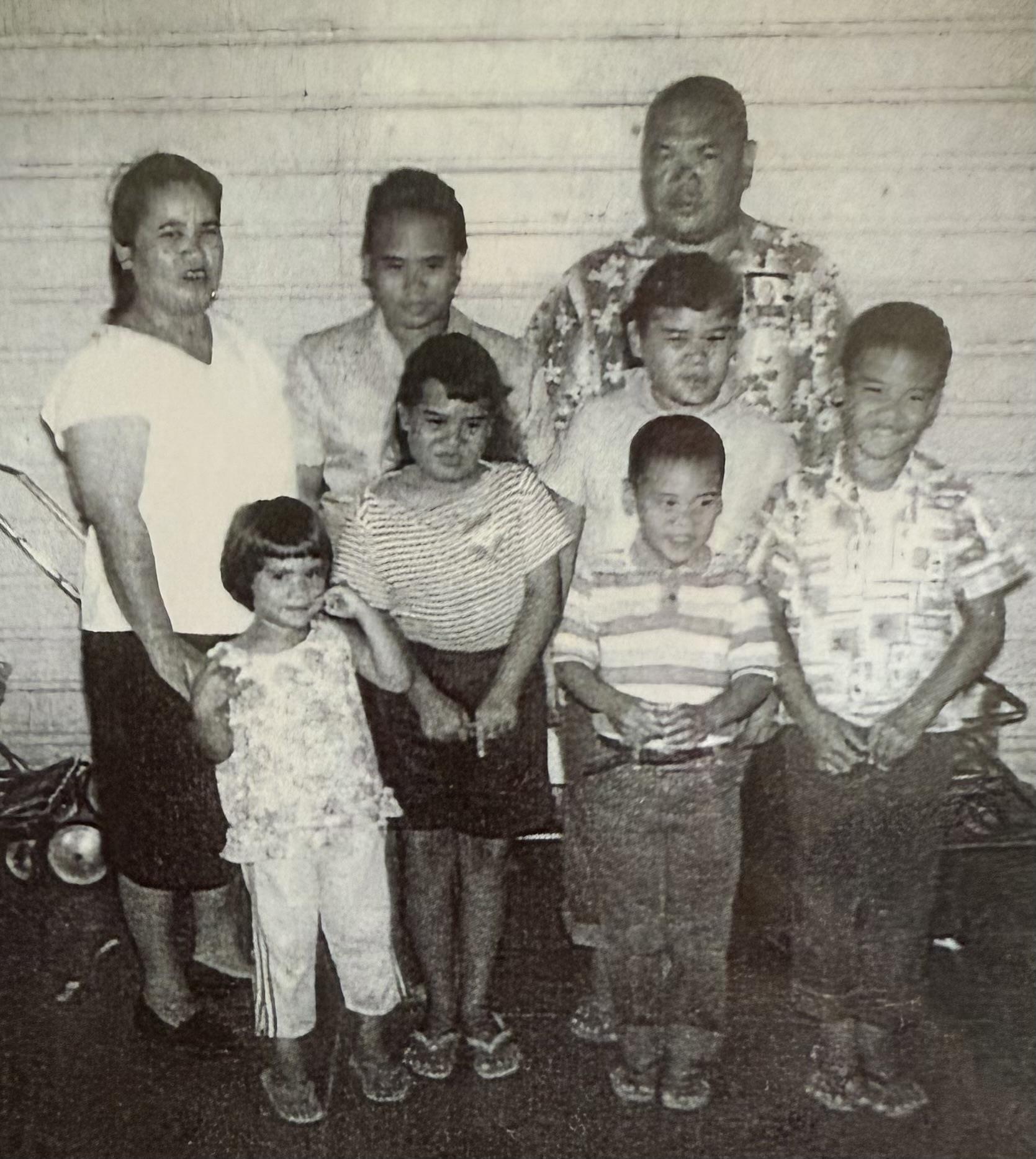 Family members gather together smiling, showcasing a mix of ages and styles in casual clothing.