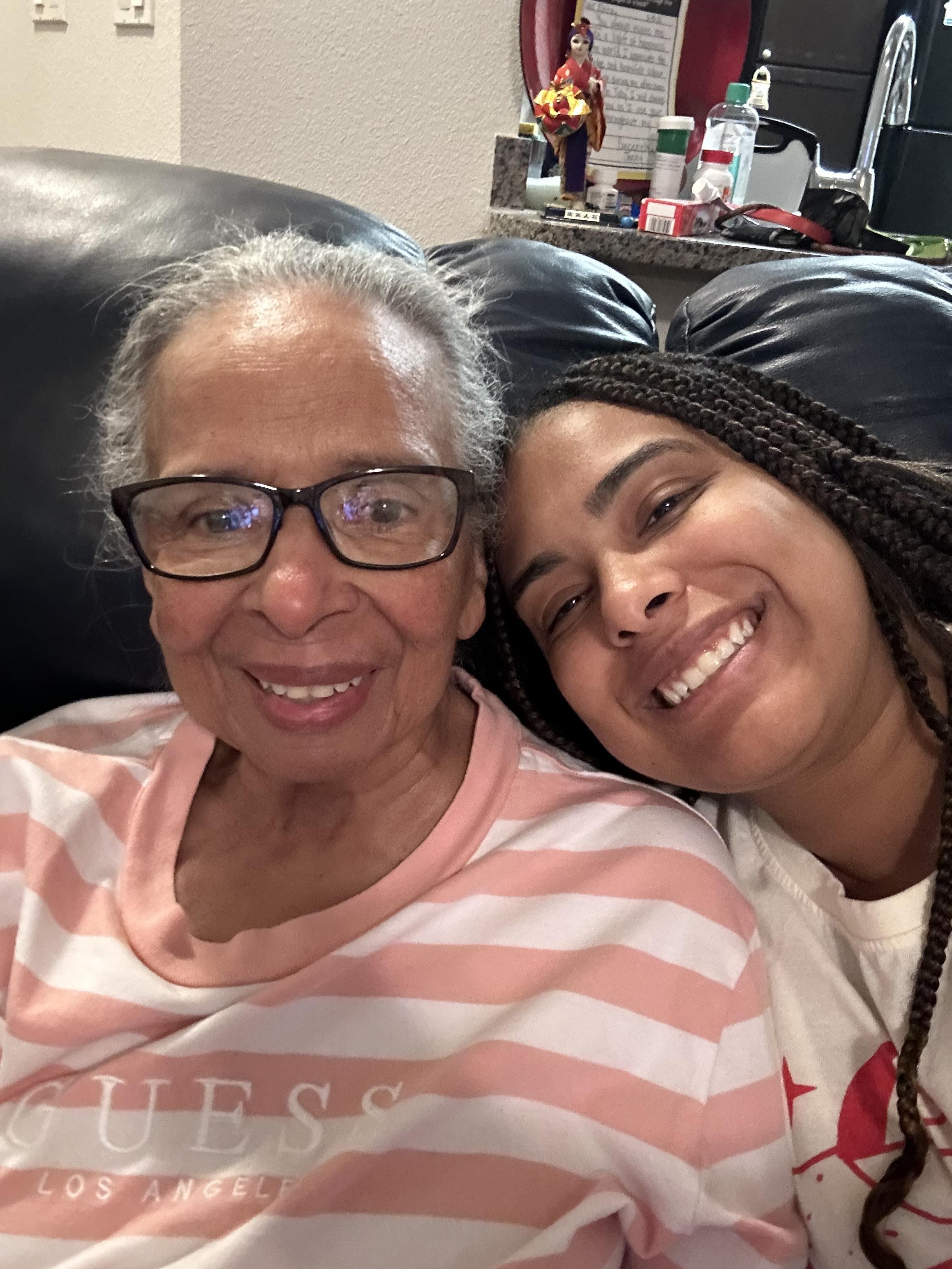 Two family members smile warmly while sitting together on a comfortable couch.