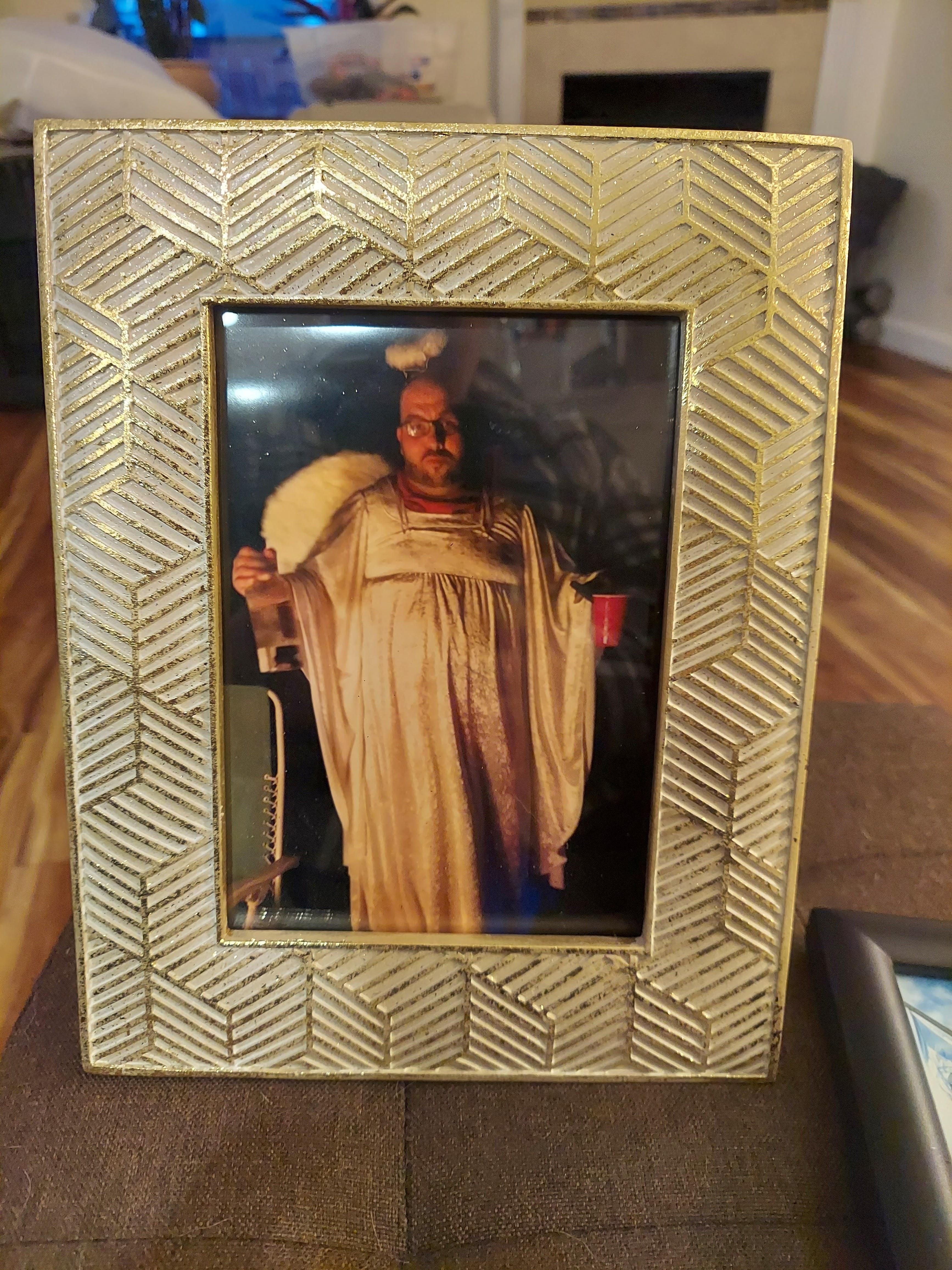 Individual in elaborate costume poses with a cup in a lively indoor environment during an event.