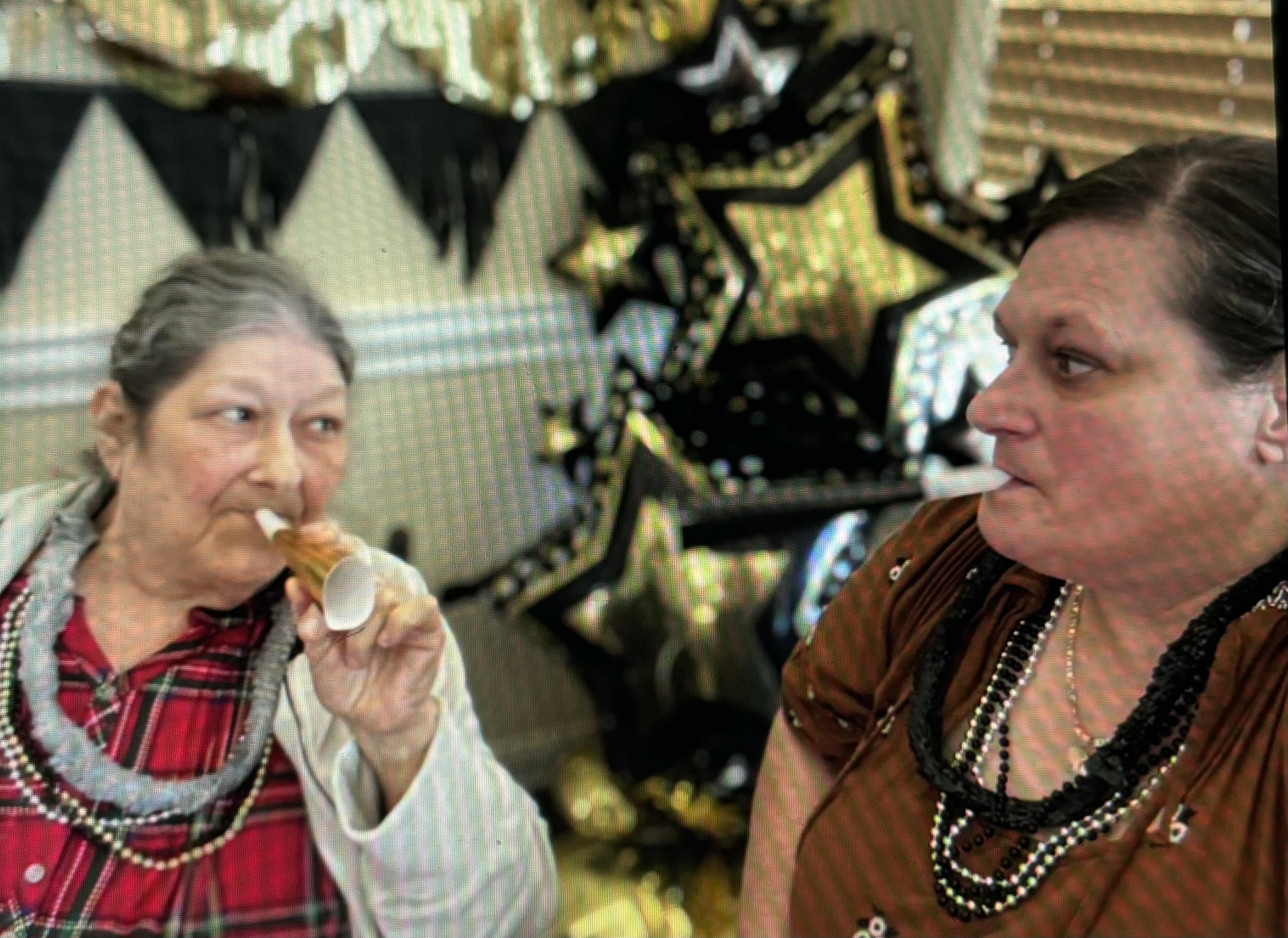 Two women in festive accessories enjoy treats at a star-decorated party.