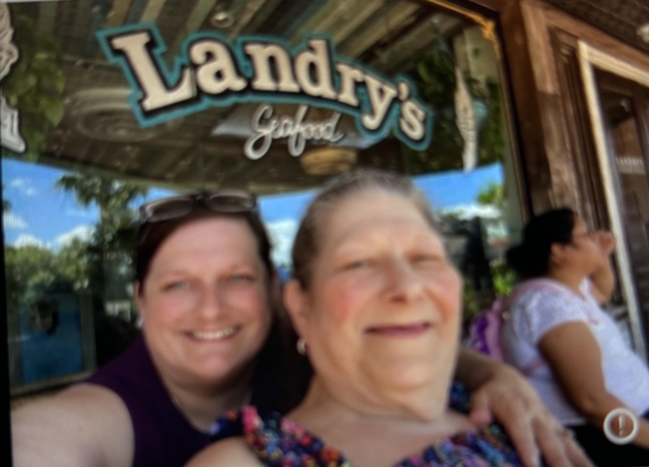 Two women enjoy a cheerful moment outside a seafood restaurant with a friendly atmosphere.