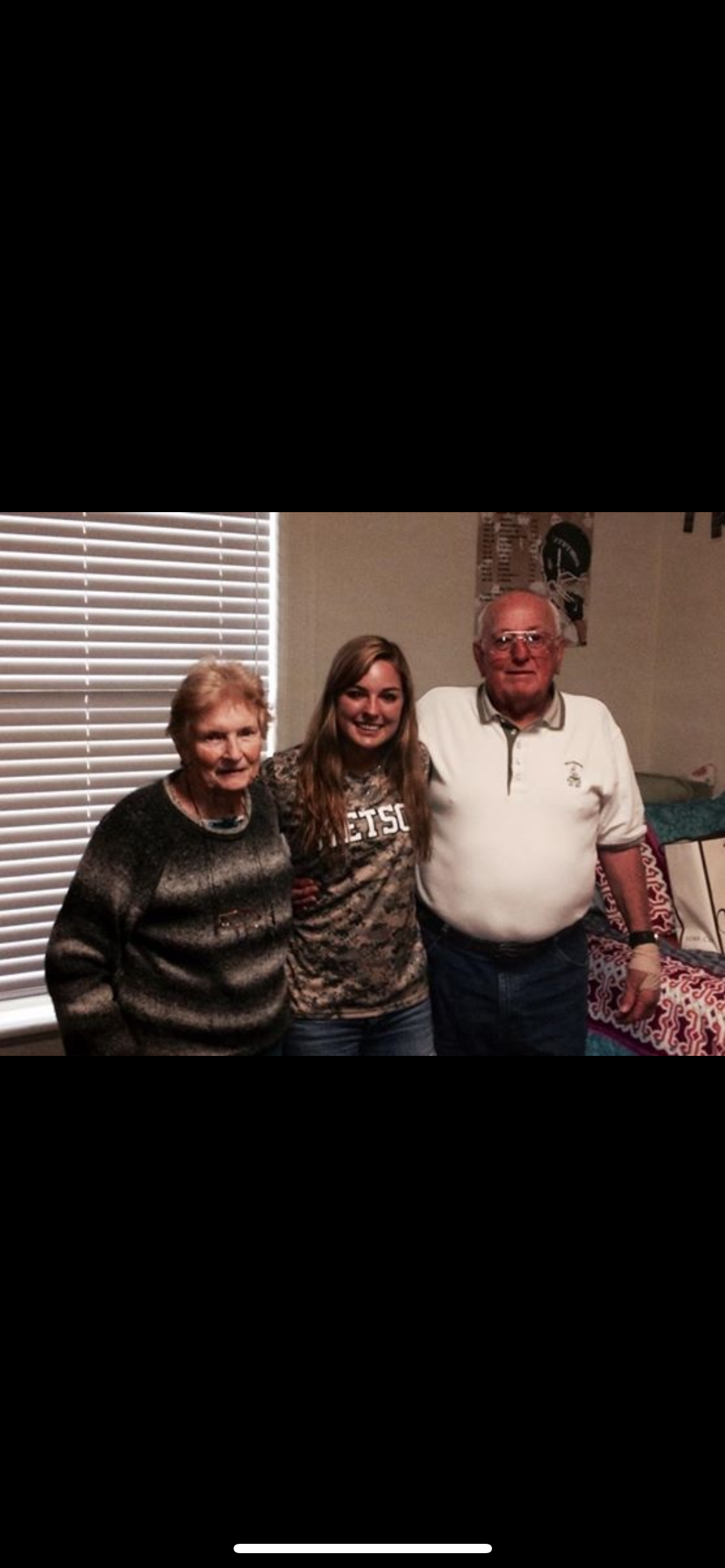Grandparents and their granddaughter pose together in a comfortable living room.