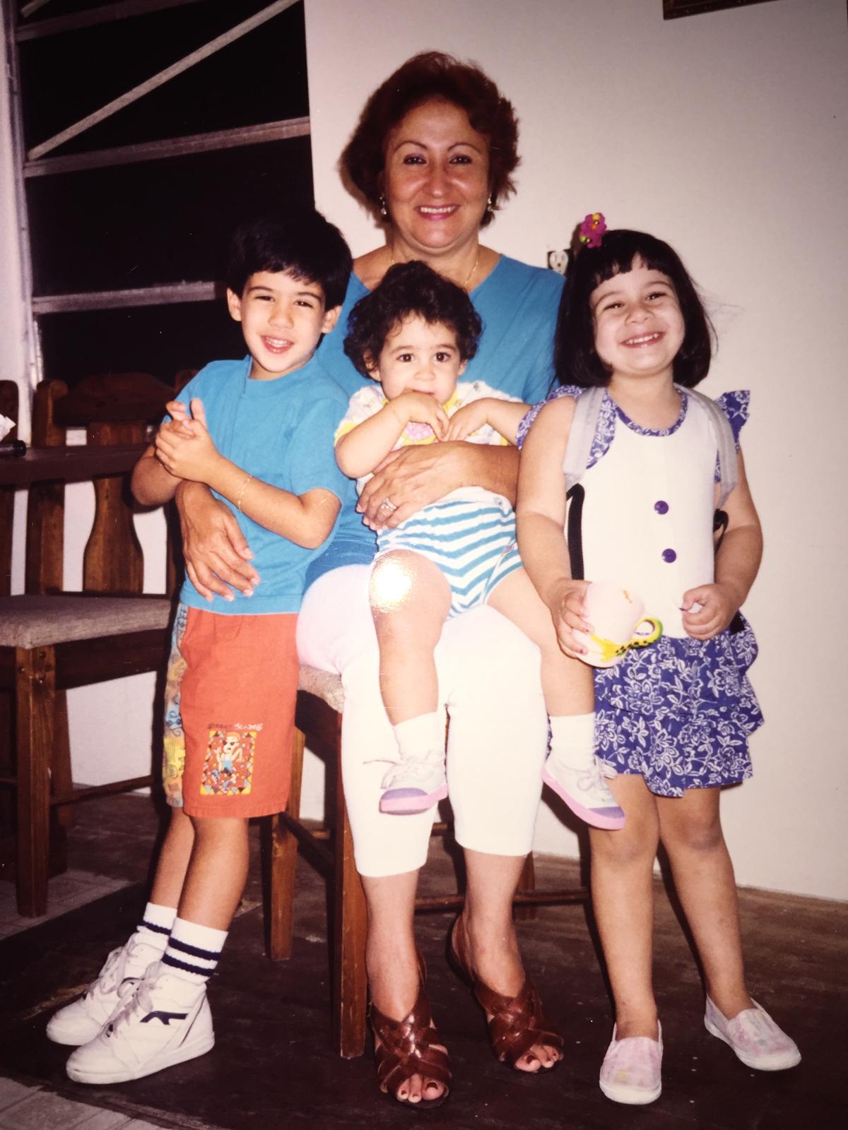 Three children happily pose with their grandmother in a warm, inviting indoor environment.