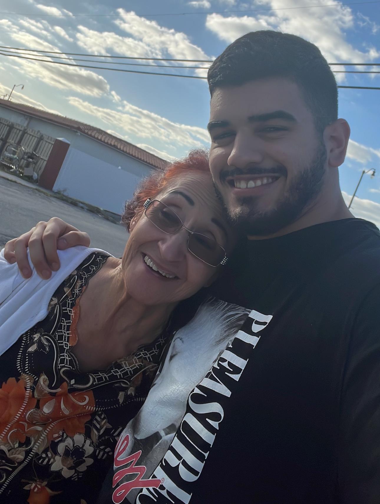 Two people smile happily together, enjoying their time outdoors in a warm setting with clear skies.